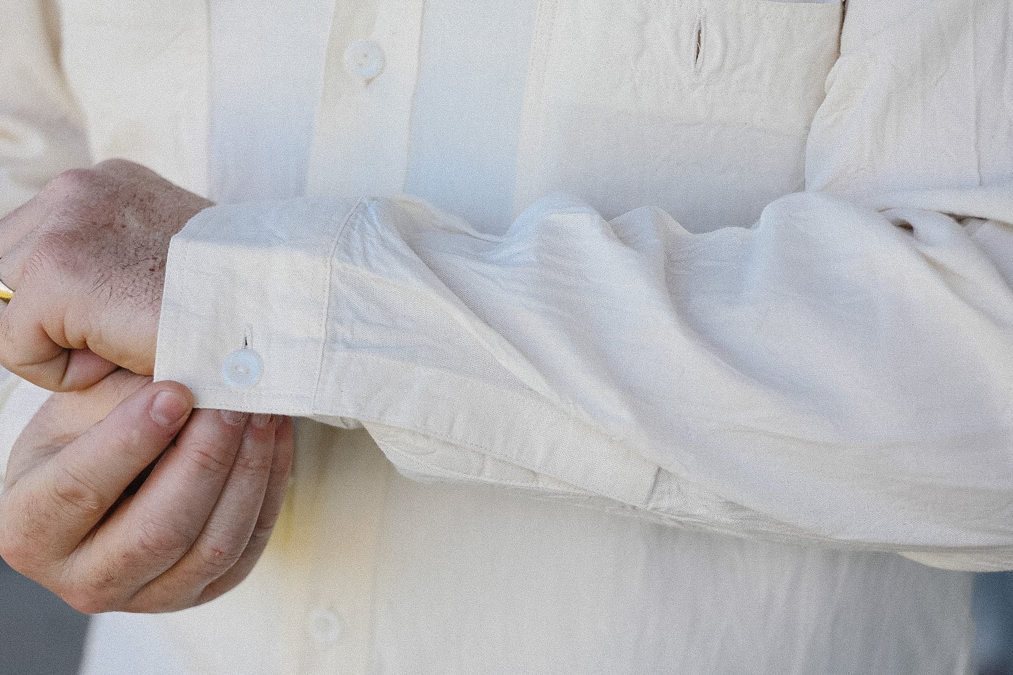 Close-up of a person adjusting the cuff of a white shirt.
