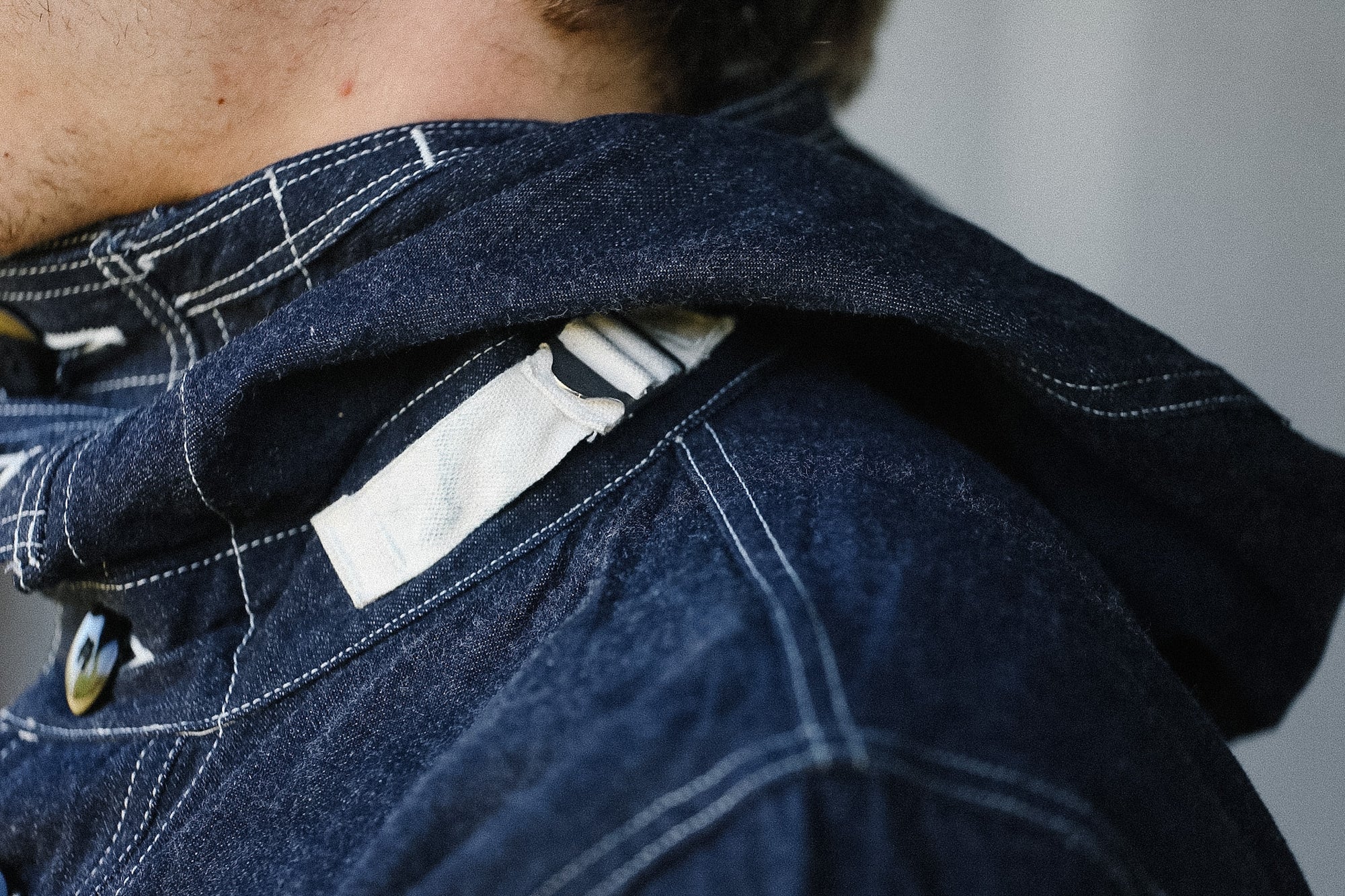 Close-up of a person wearing a dark blue denim jacket with a blurred background