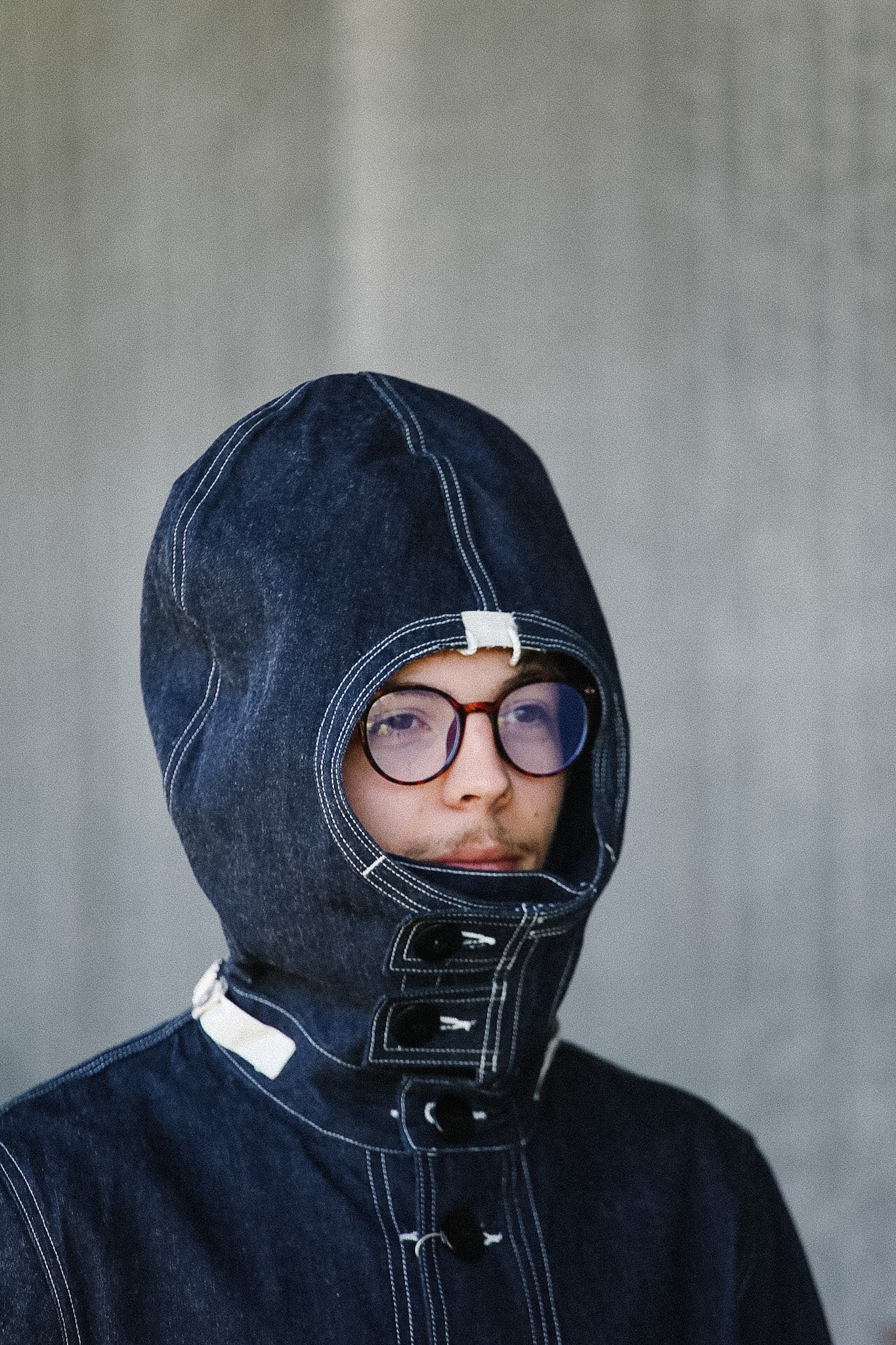 Person wearing a dark blue hooded garment against a plain background