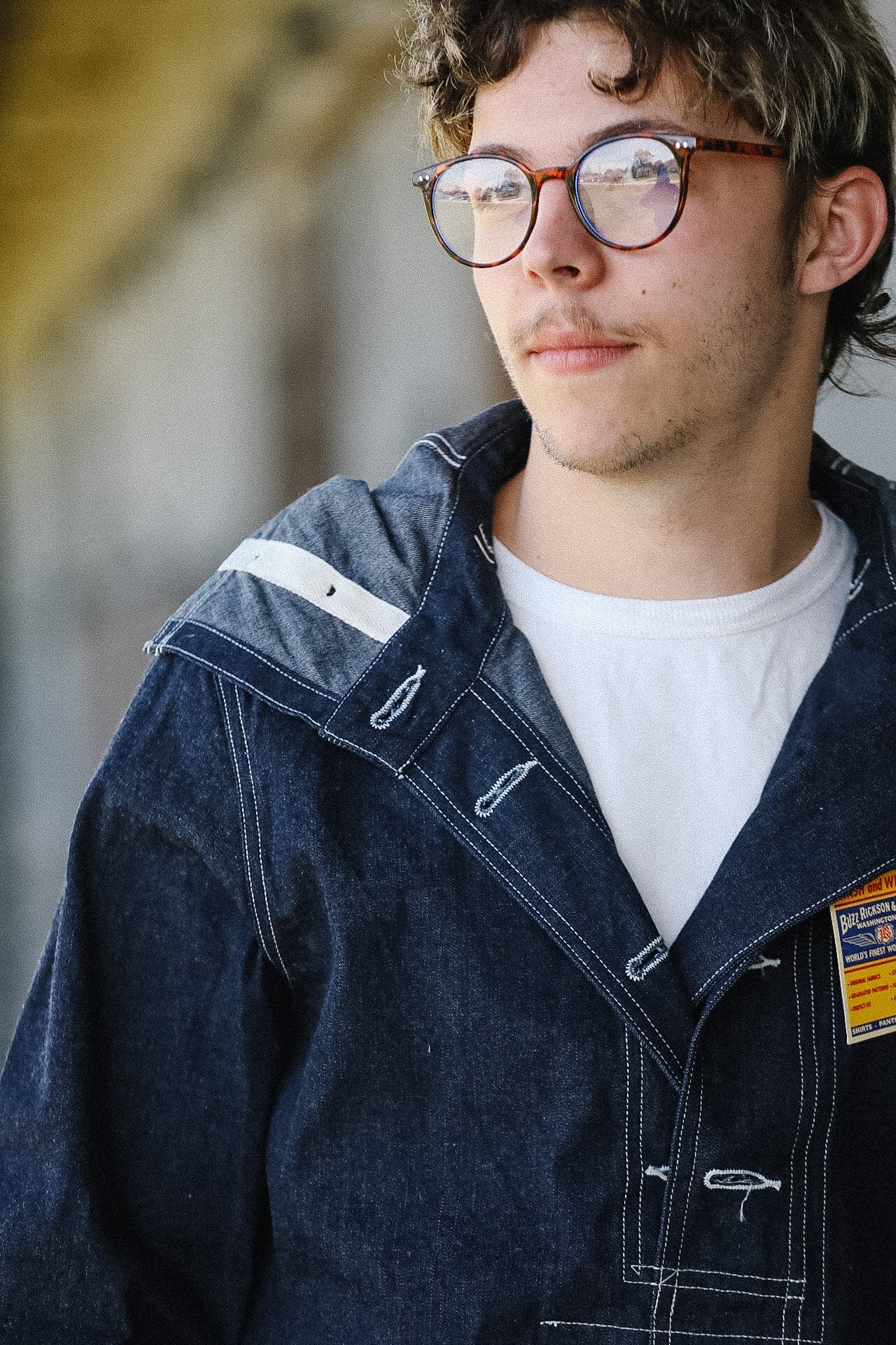 Person wearing a blue jacket with a white shirt underneath, standing outdoors.