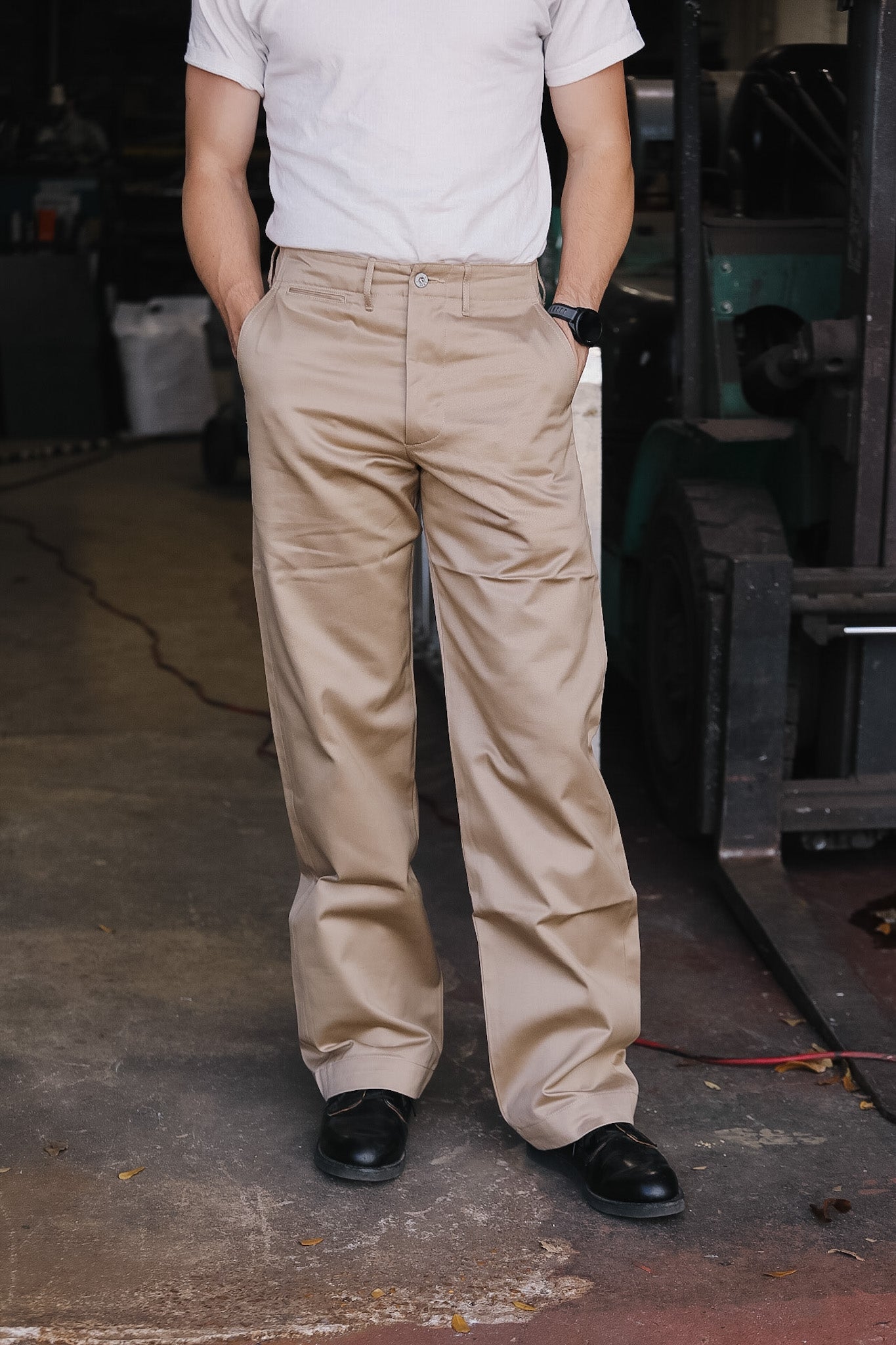 Person wearing beige pants and a white shirt in an industrial setting