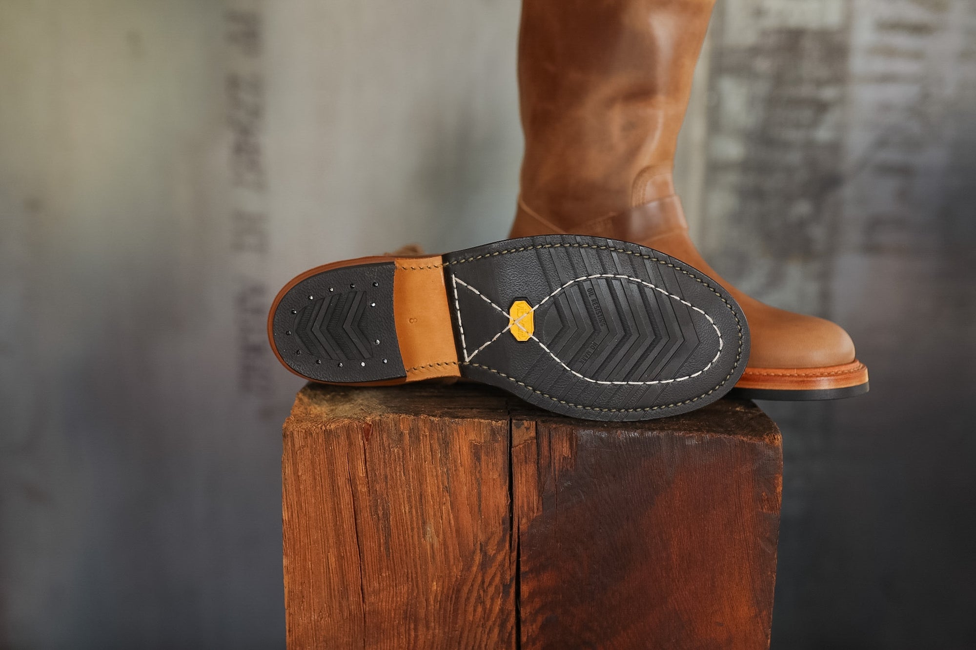 Close-up of a brown leather boot sole on a wooden block with a blurred background
