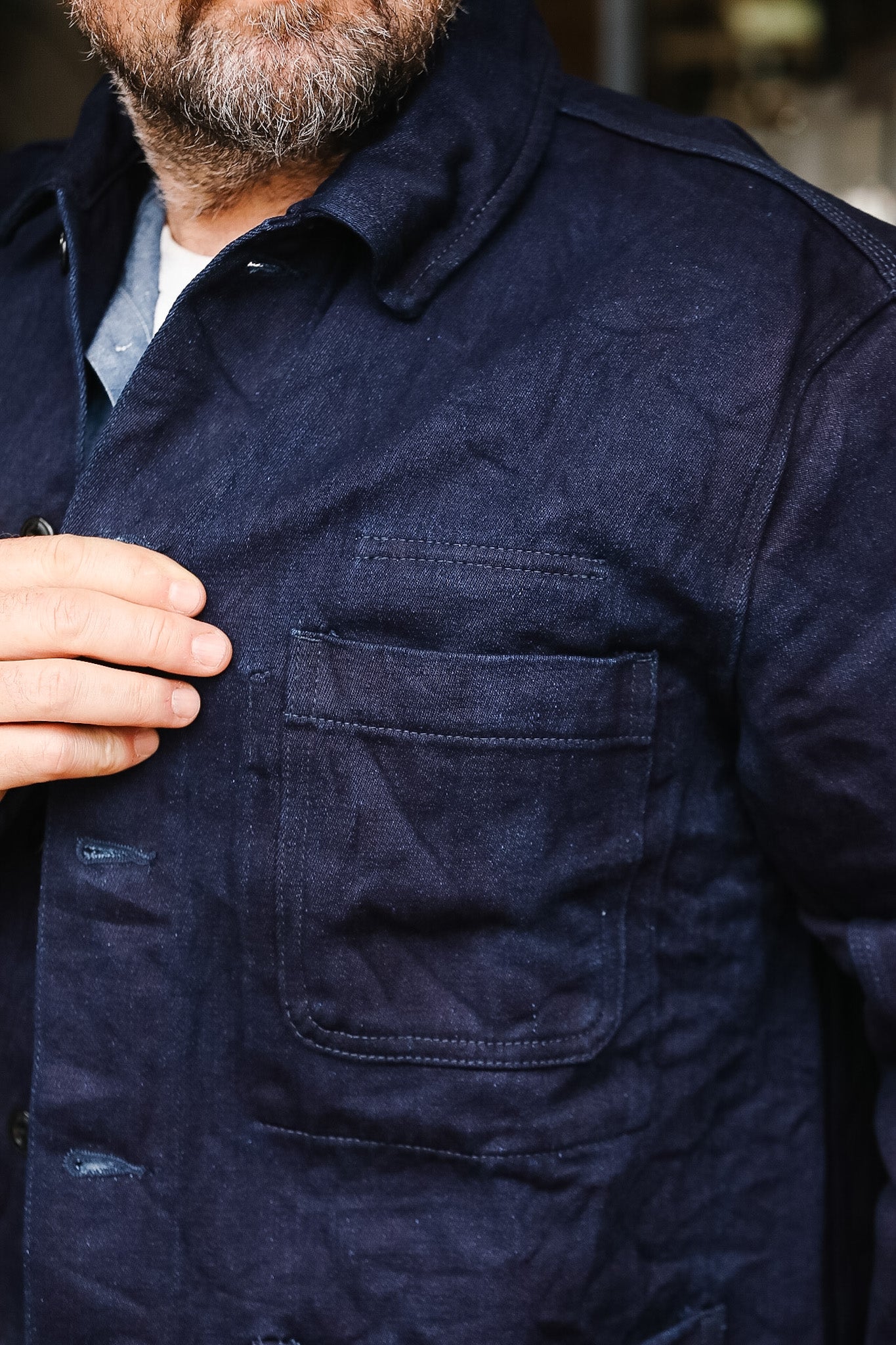 Close-up of a person wearing a dark blue jacket with a pocket.