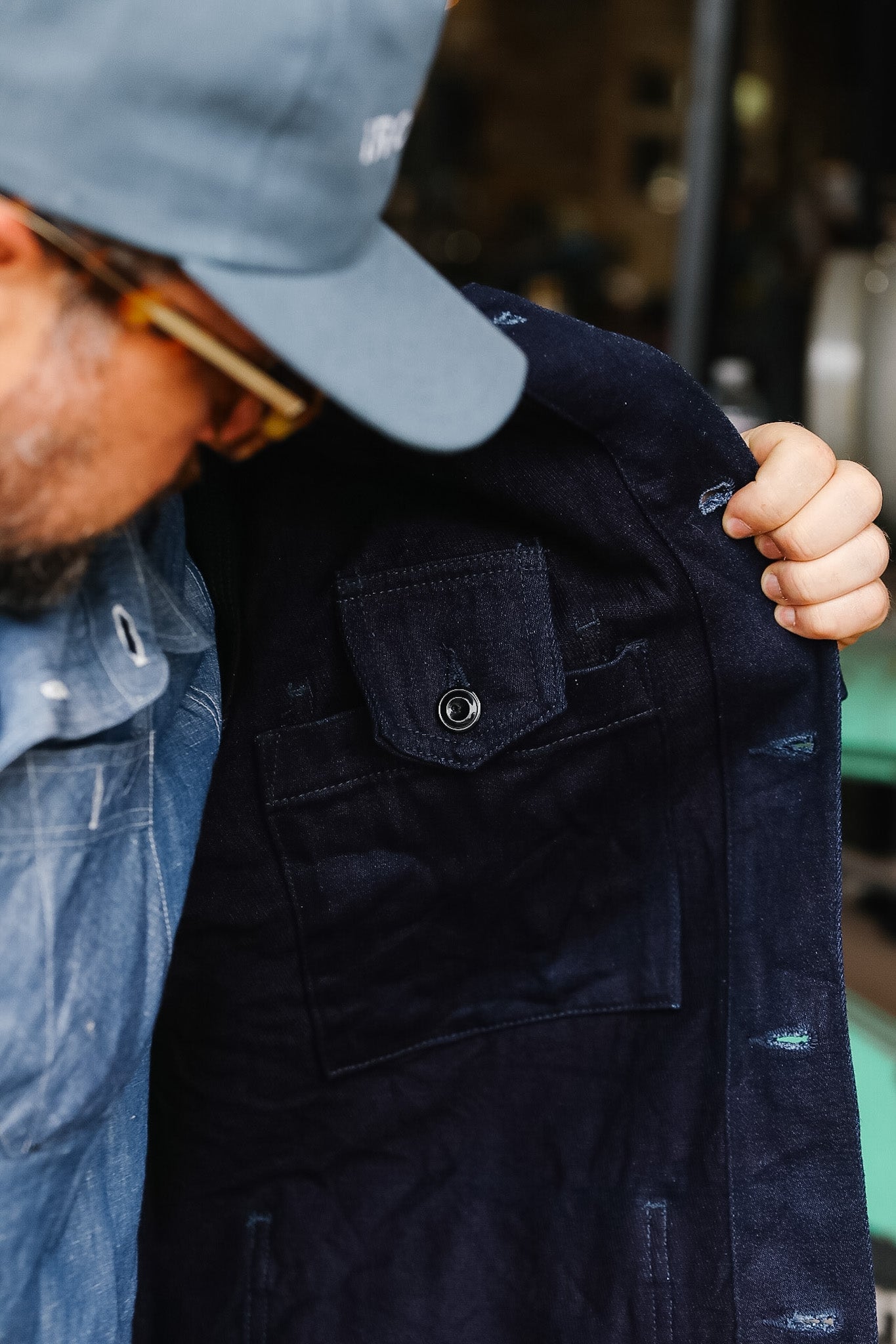 Person wearing a navy jacket with visible branding, holding it up.