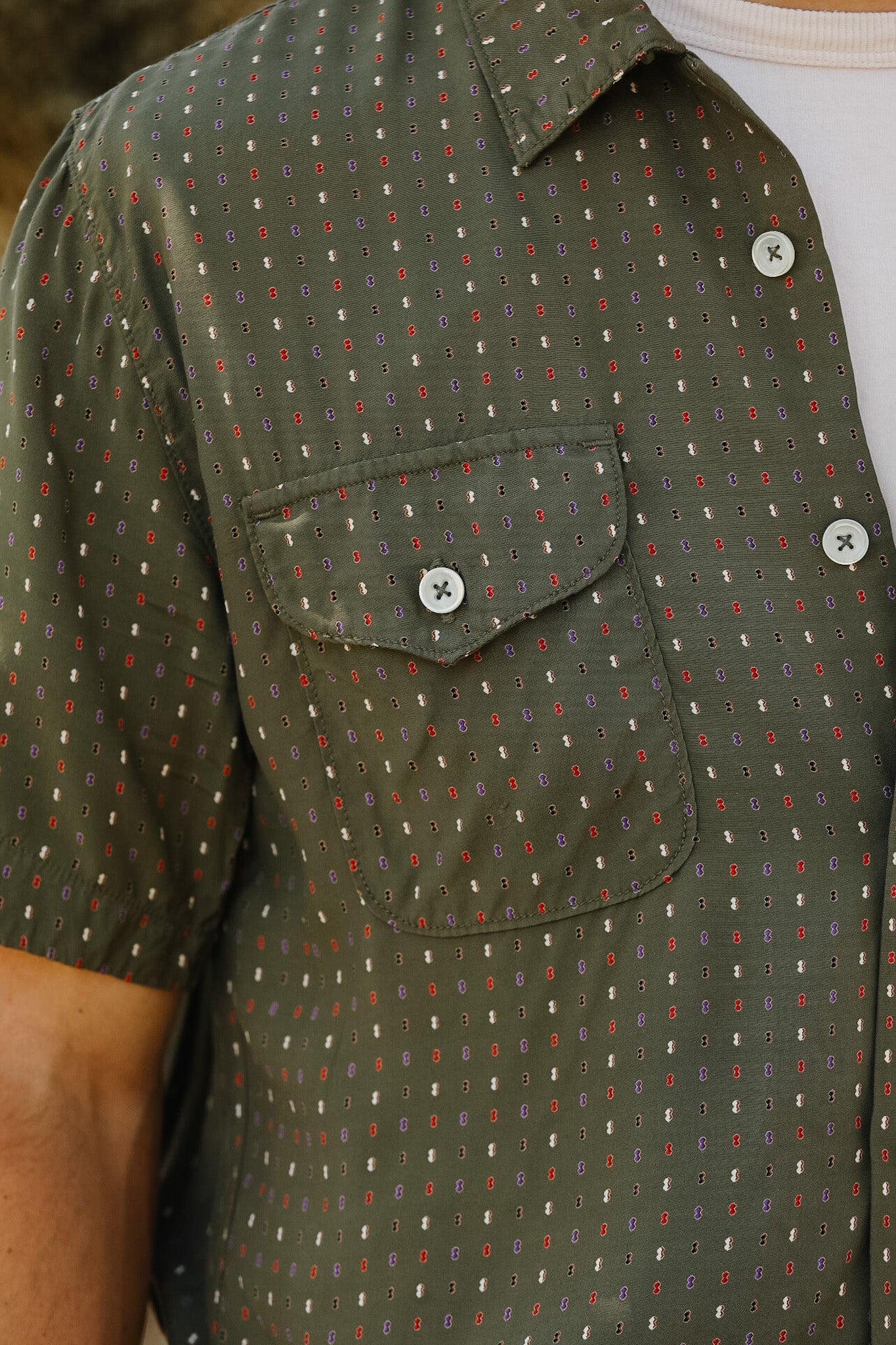 Close-up of a green patterned shirt with a pocket and buttons.
