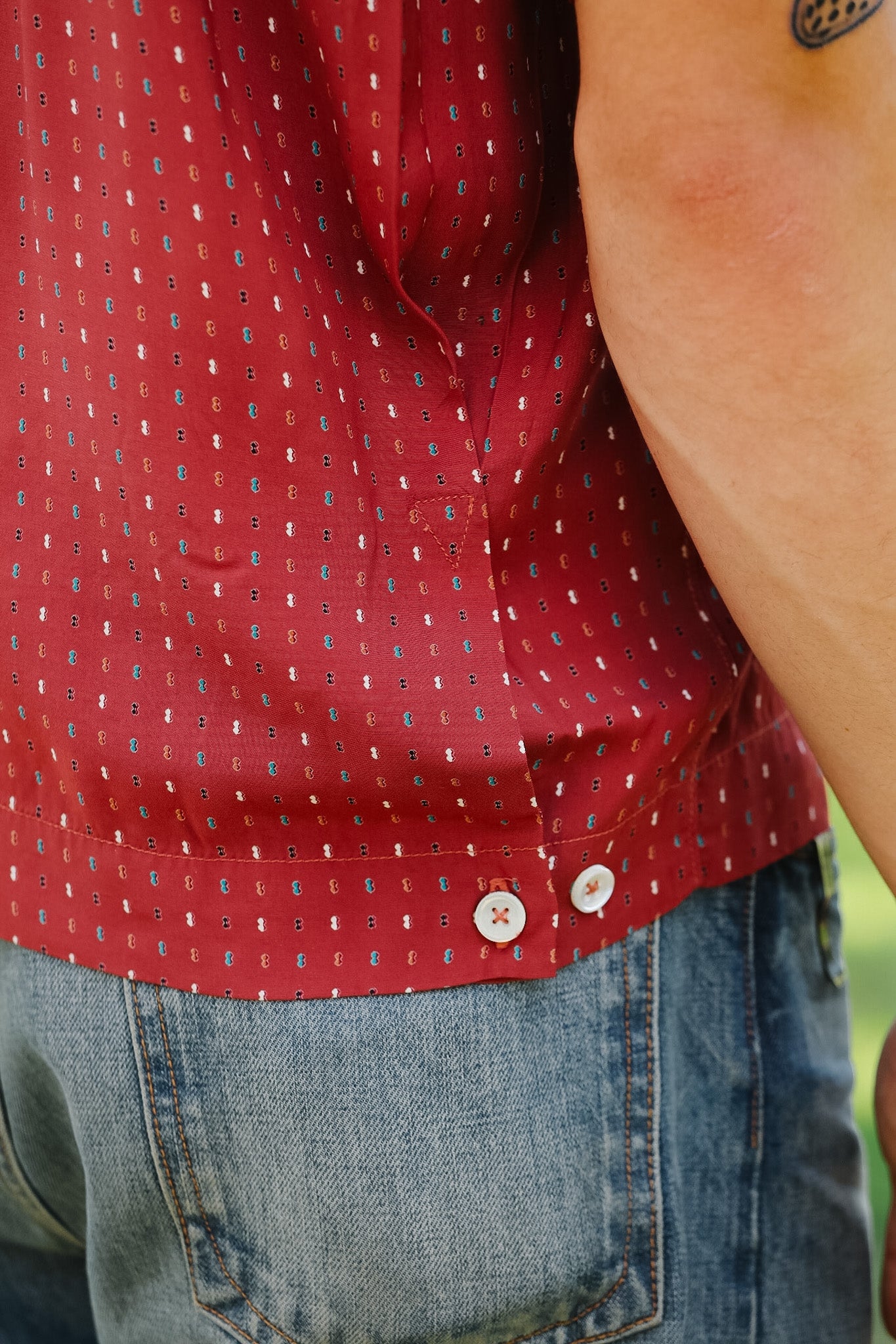 Red patterned shirt and blue jeans worn by a person outdoors