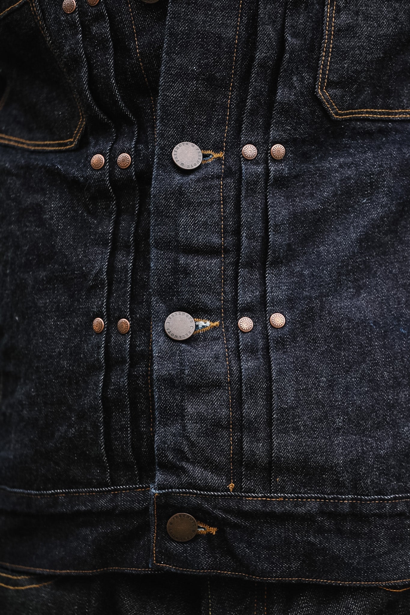 Close-up of a dark denim jacket with button details