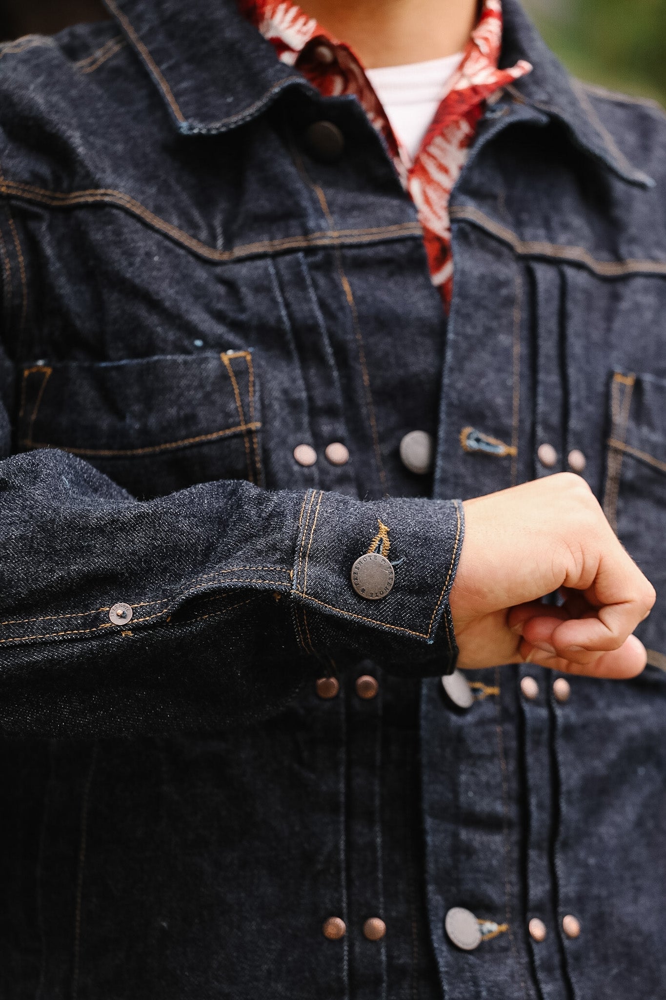 Close-up of a person wearing a dark denim jacket with a blurred background