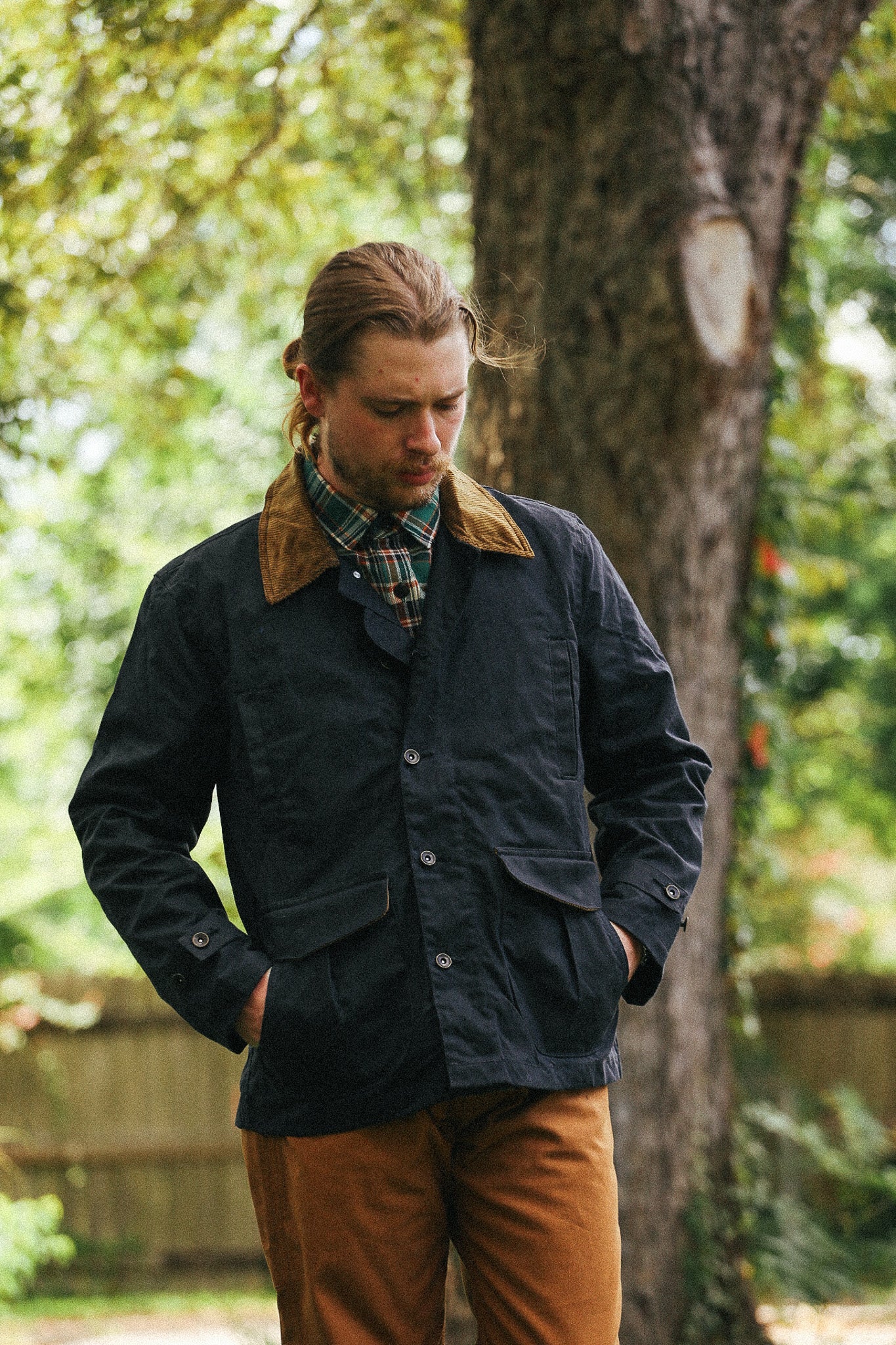 man with black jacket with showing pocket detail against a green natural background