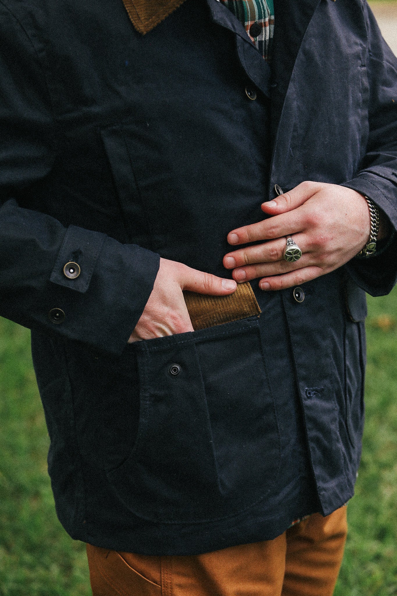man with black jacket with showing pocket detail against a green natural background