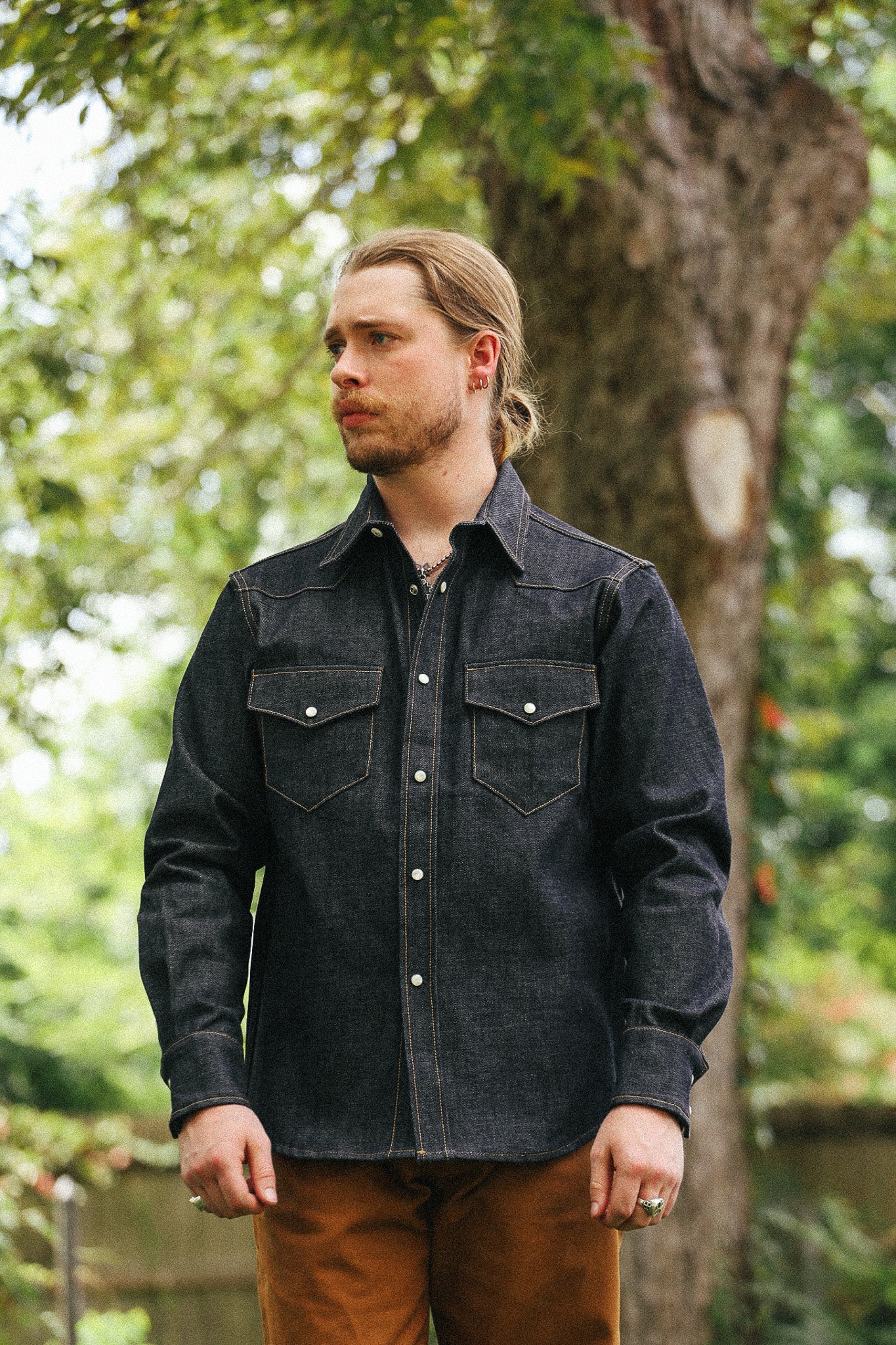 man with denim shirt against a green natural background