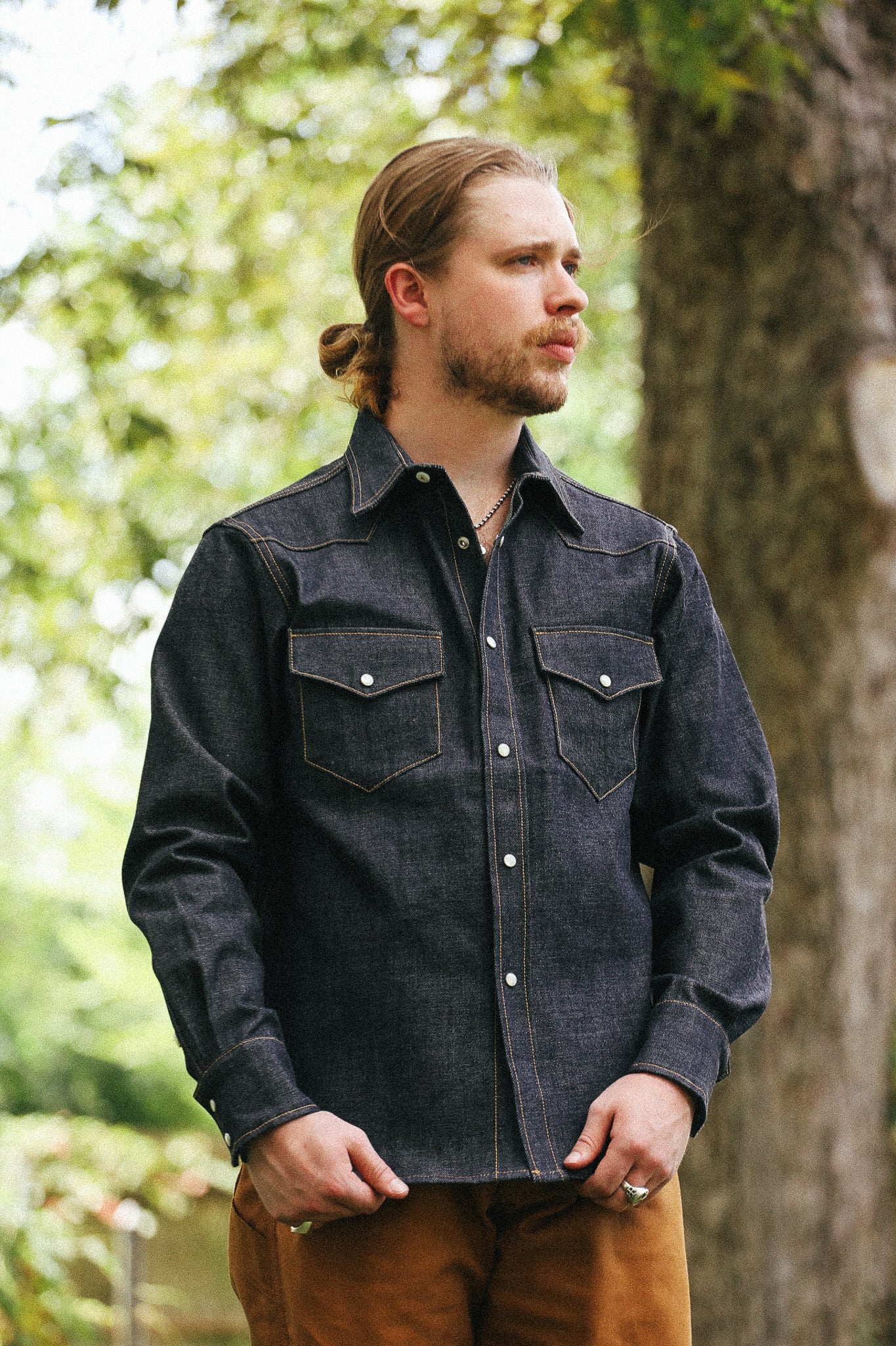 man with denim shirt against a green natural background