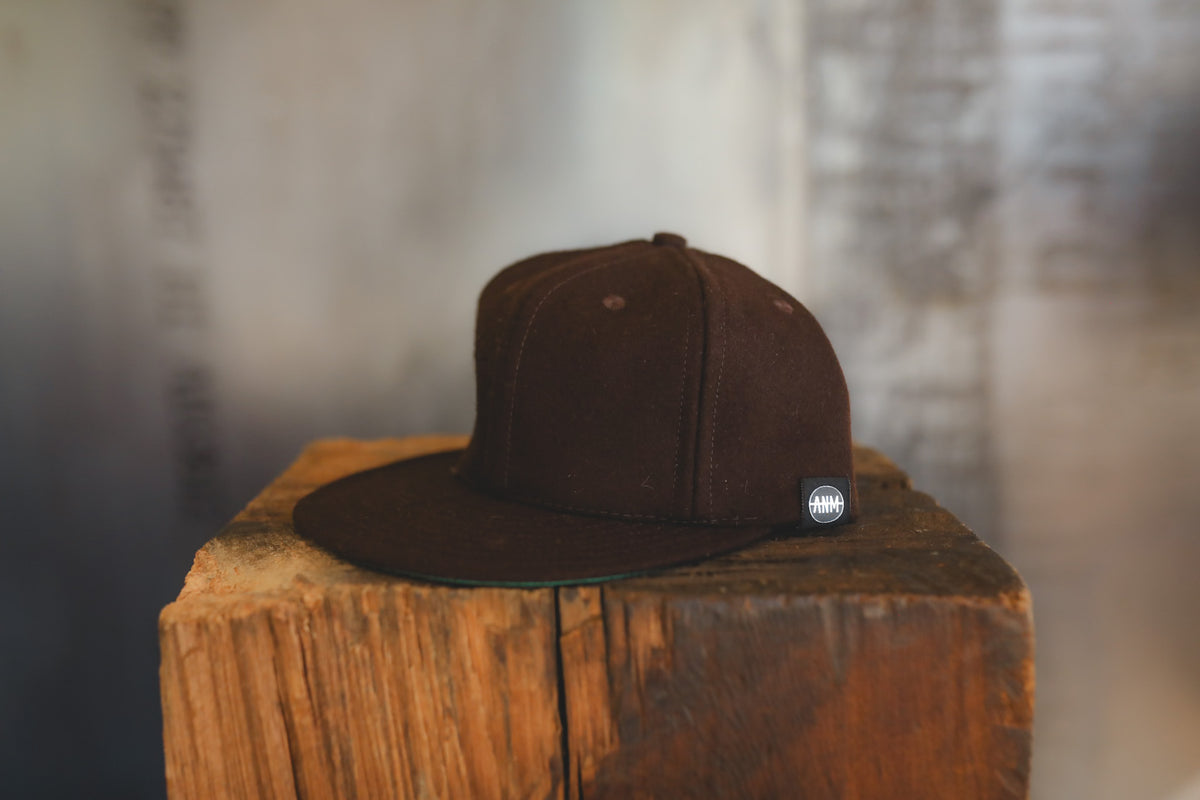 Up close of a brown baseball cap on wood block 