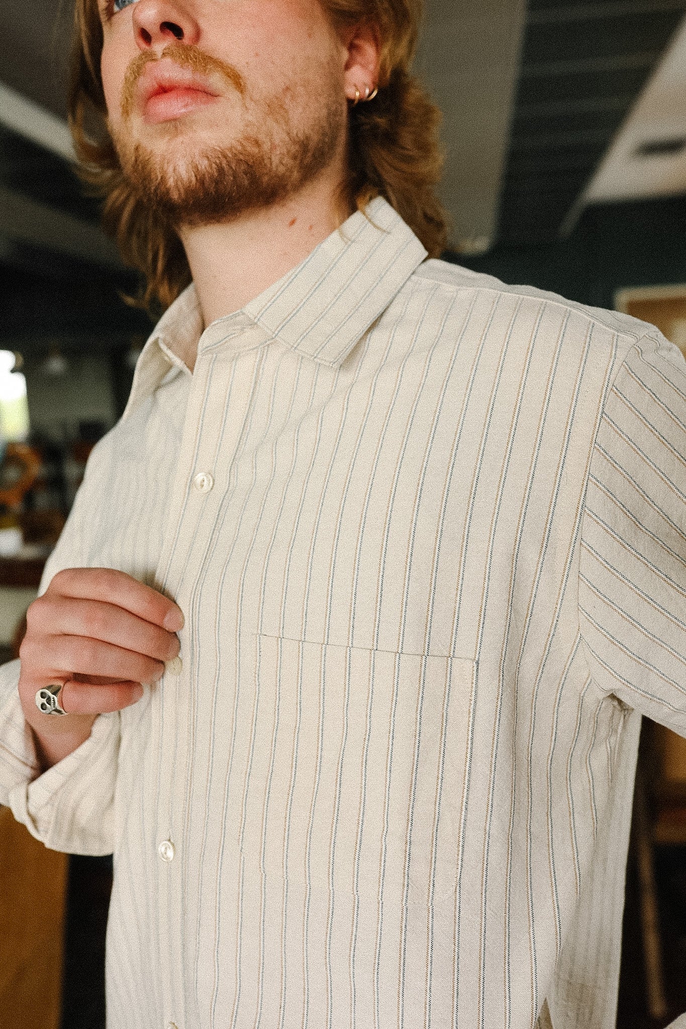 Man wearing a light-colored ribbed shirt with a blurred indoor background