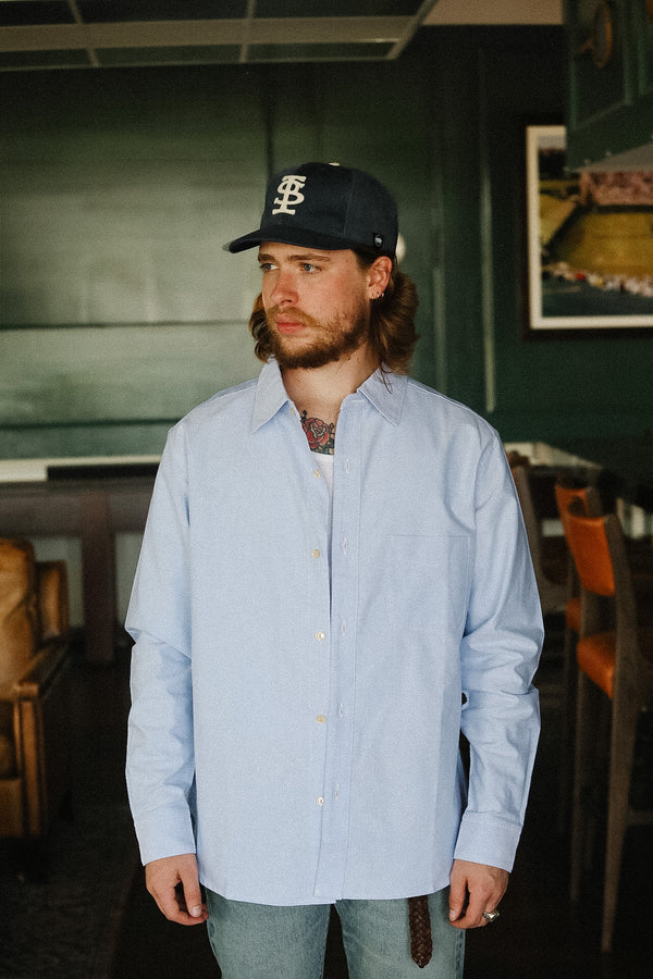 Man wearing a blue shirt and black cap in an indoor setting