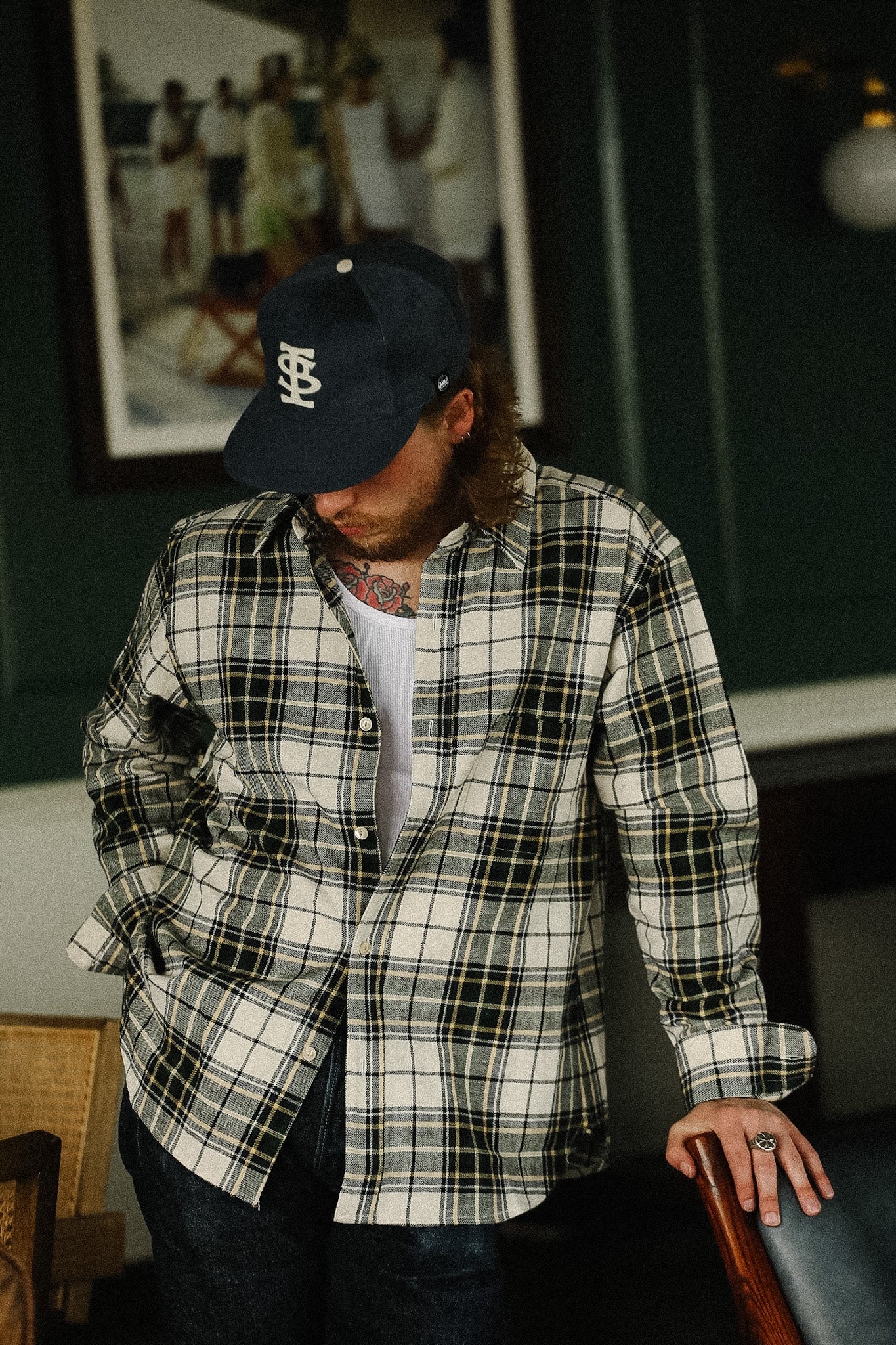 Man wearing a plaid shirt and cap in an indoor setting