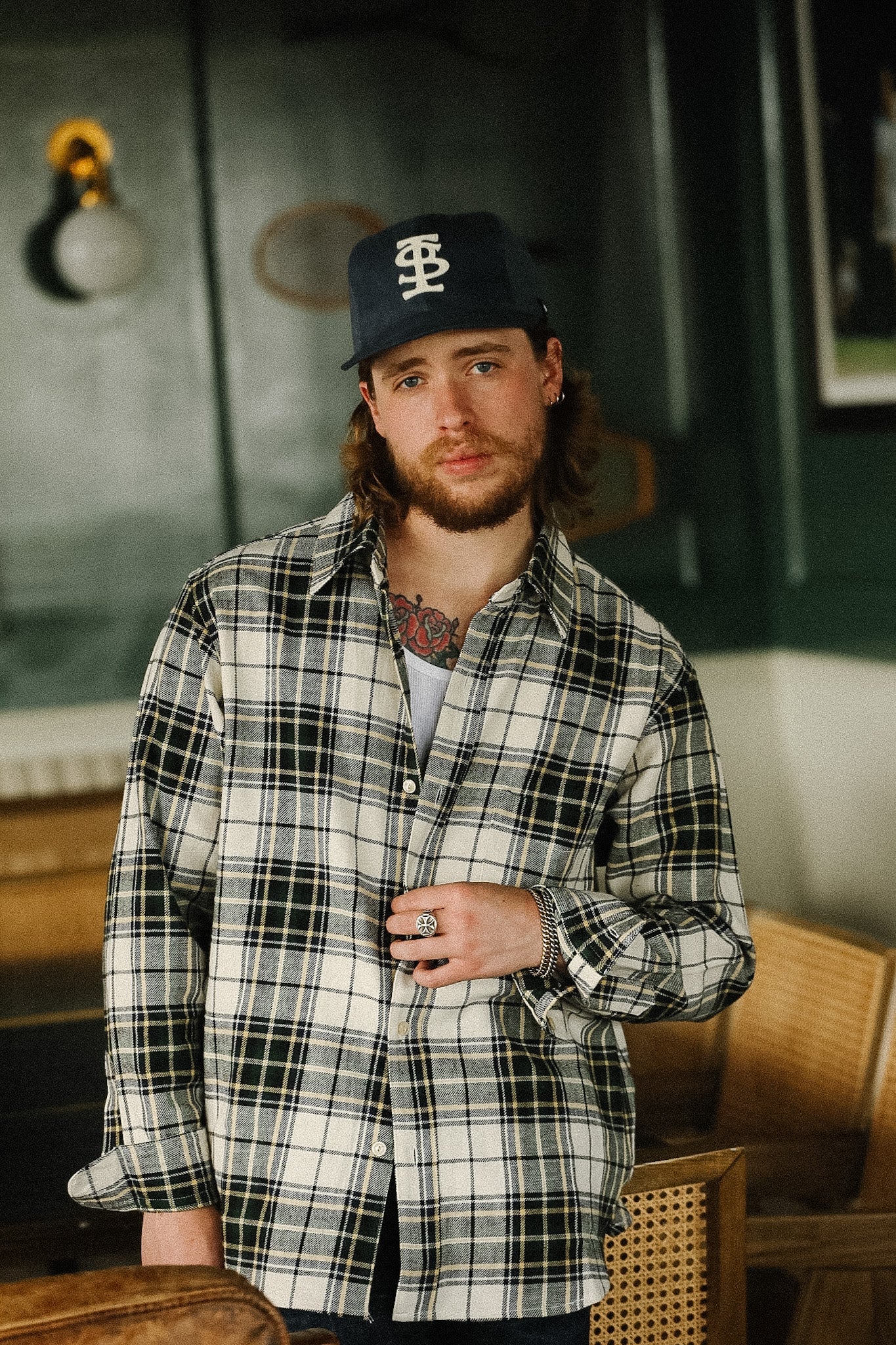 Man wearing a plaid shirt and cap indoors