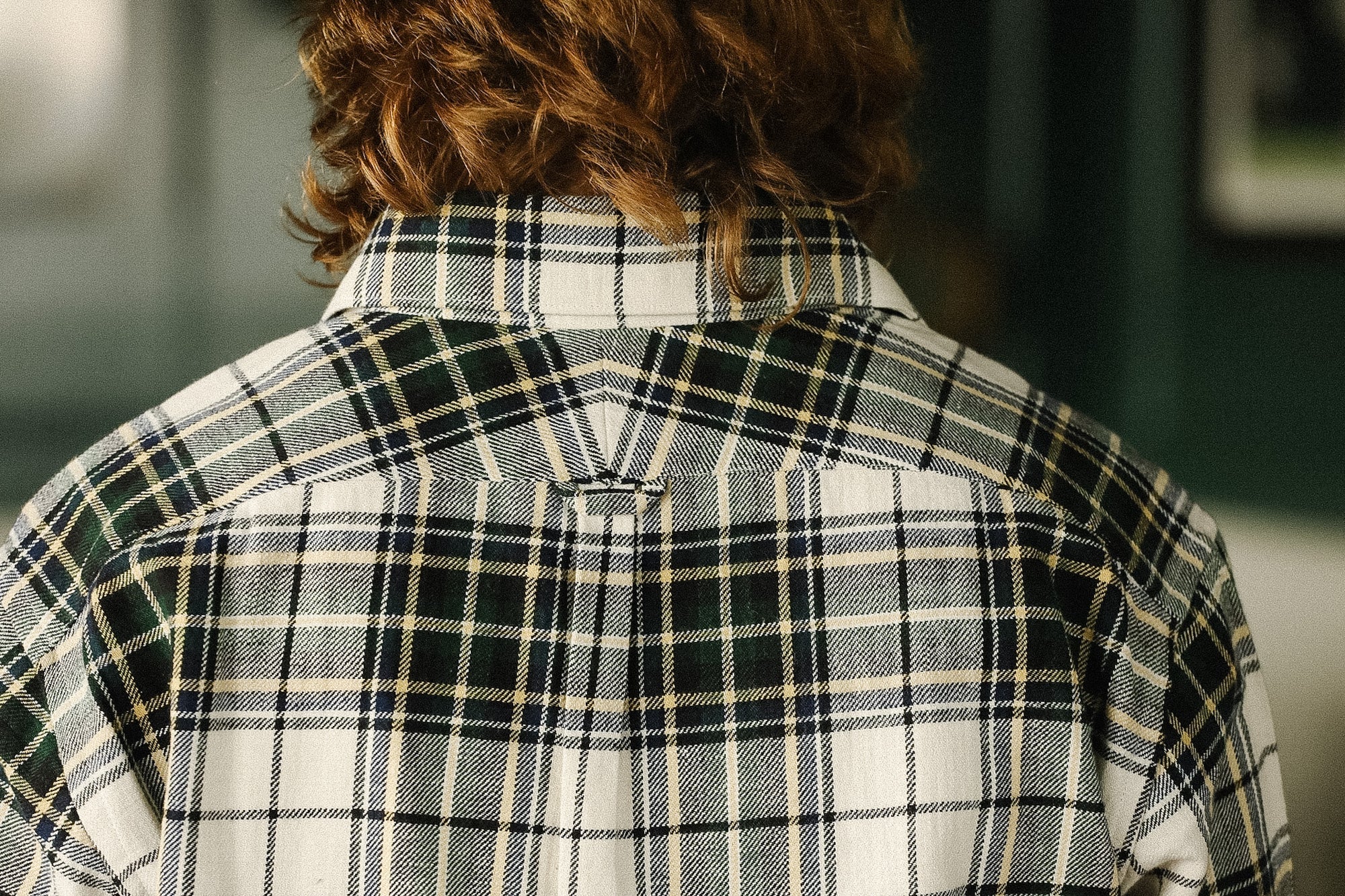 Person wearing a plaid shirt with a blurred background