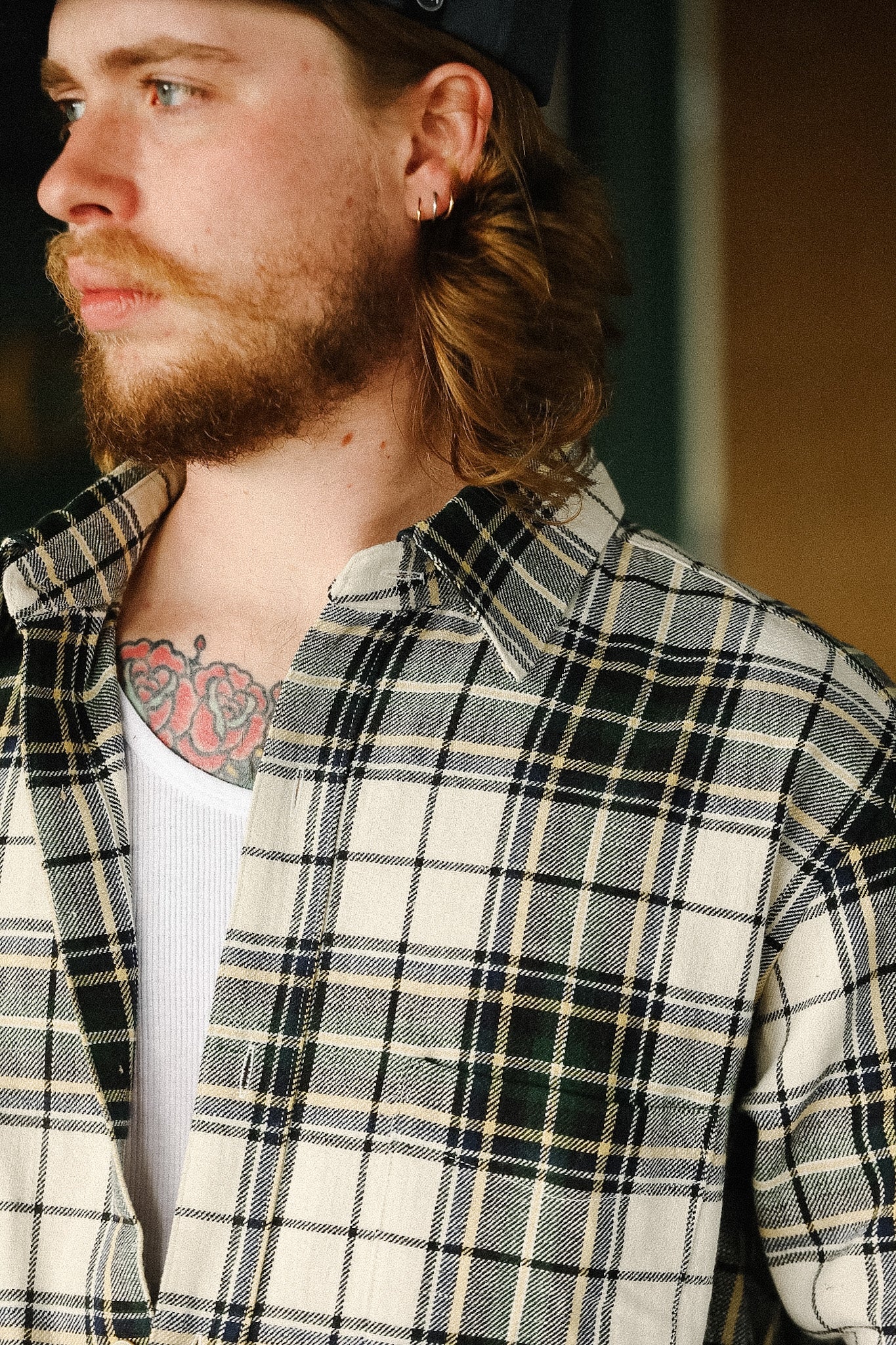 Man wearing a plaid shirt with a tattoo on his neck