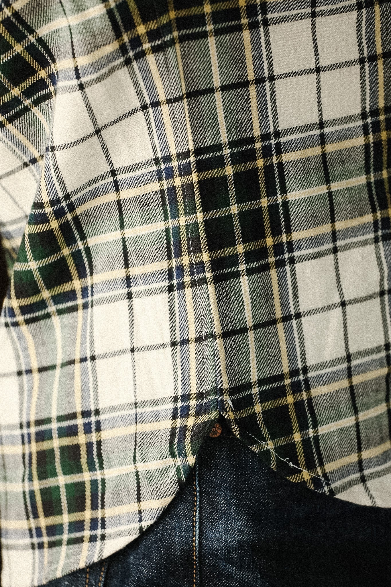 Close-up of a plaid shirt with a button, showing a focus on texture and pattern.