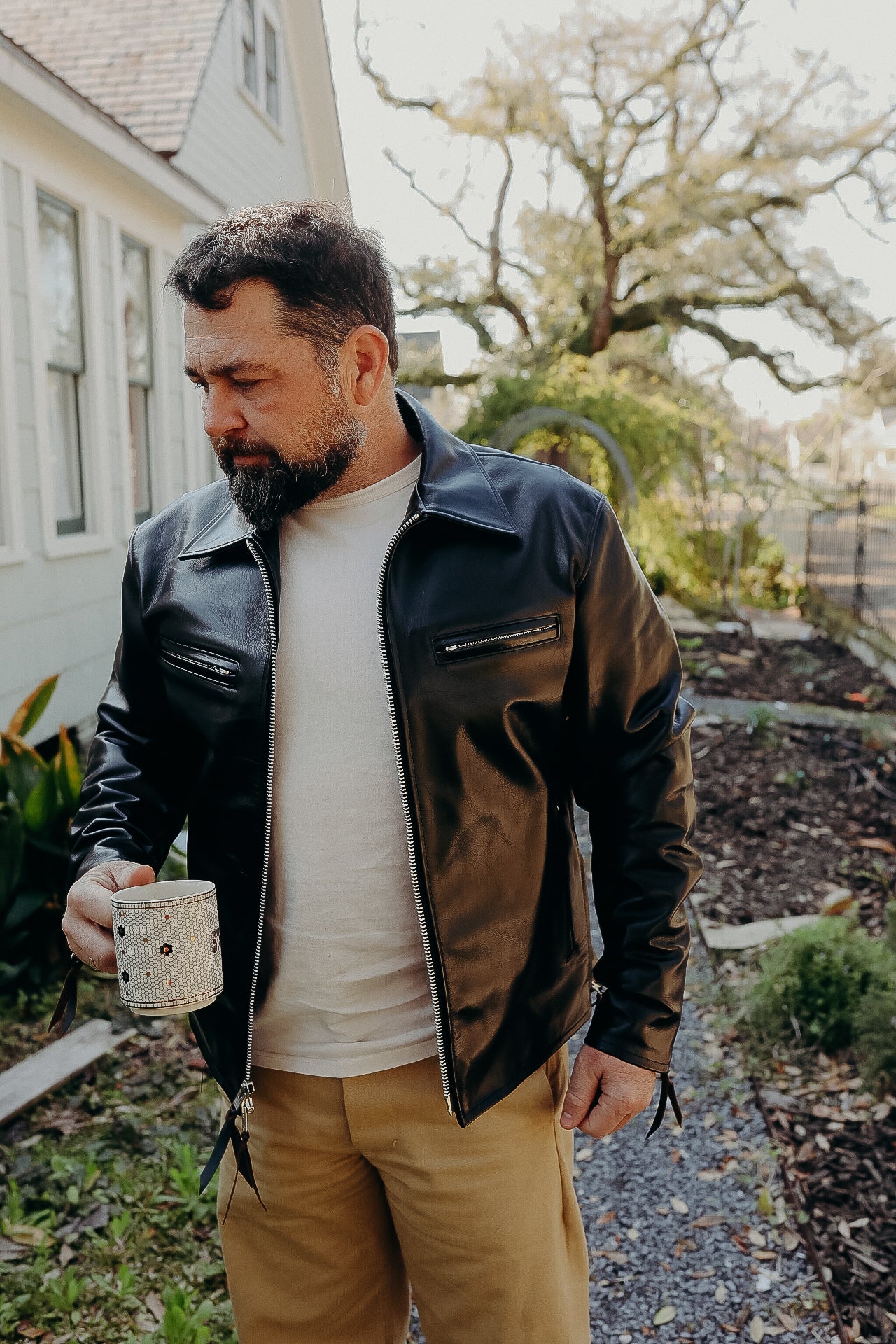 A person wearing a black horsehide rider's jacket with a collar, standing outdoors.