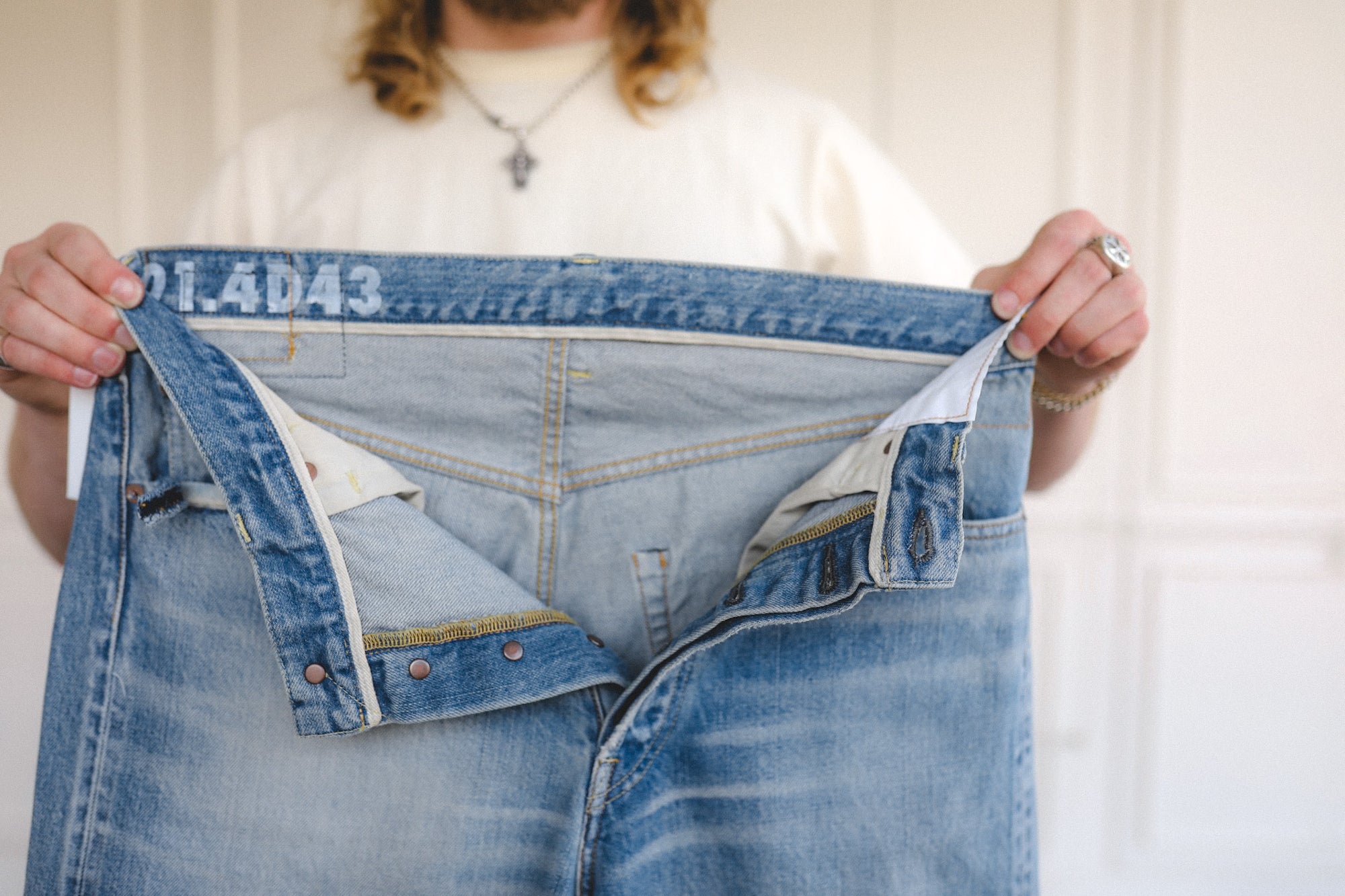 Person holding up a pair of blue jeans with size label