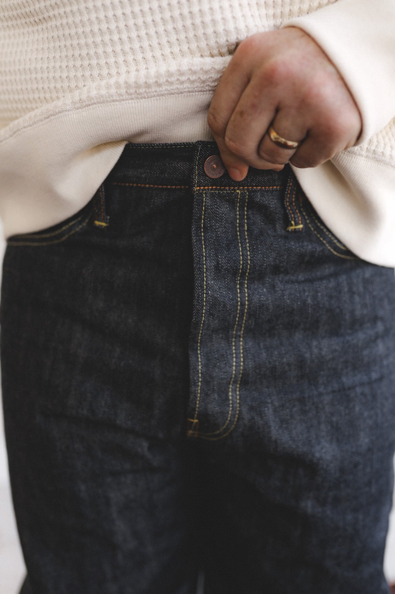 Person wearing dark jeans with a neutral background