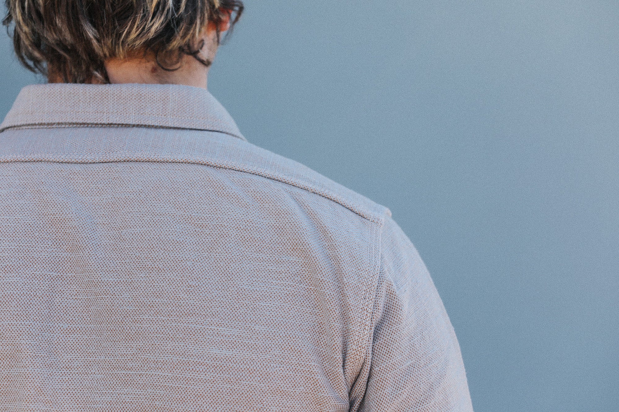 Person wearing a light brown jacket against a blue sky