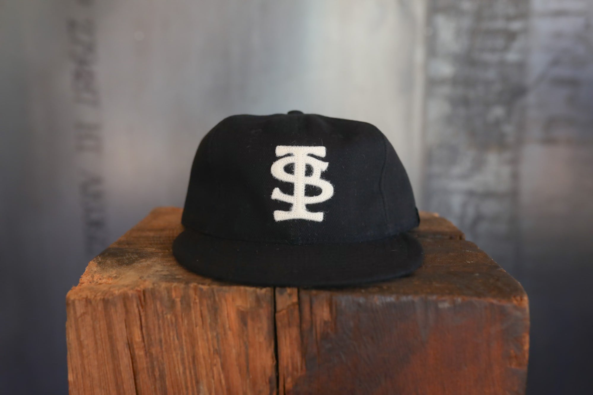 Black cap with a white logo on a wooden block against a blurred background