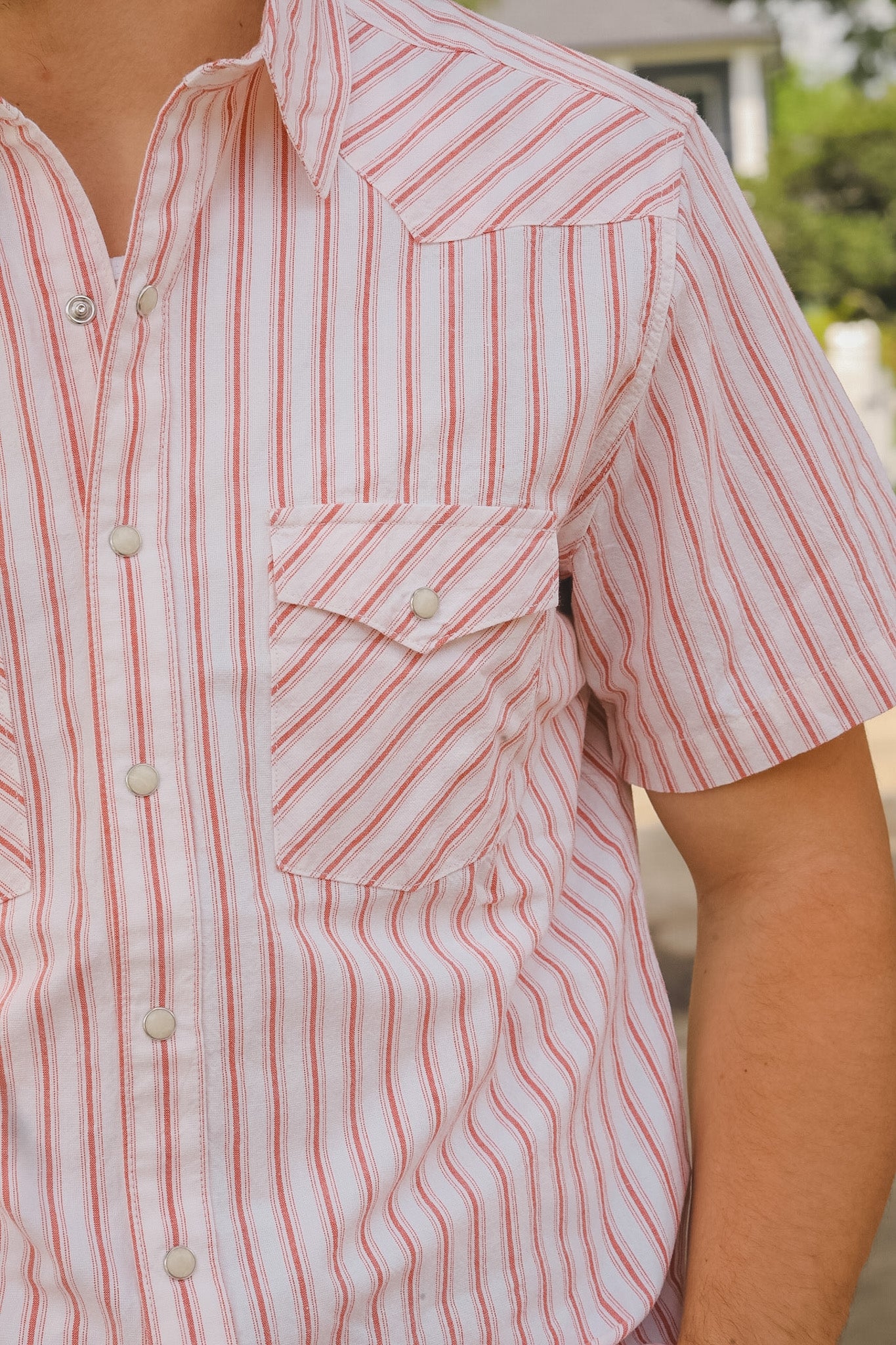 Close-up of a person wearing a red and white striped shirt with a blurred background