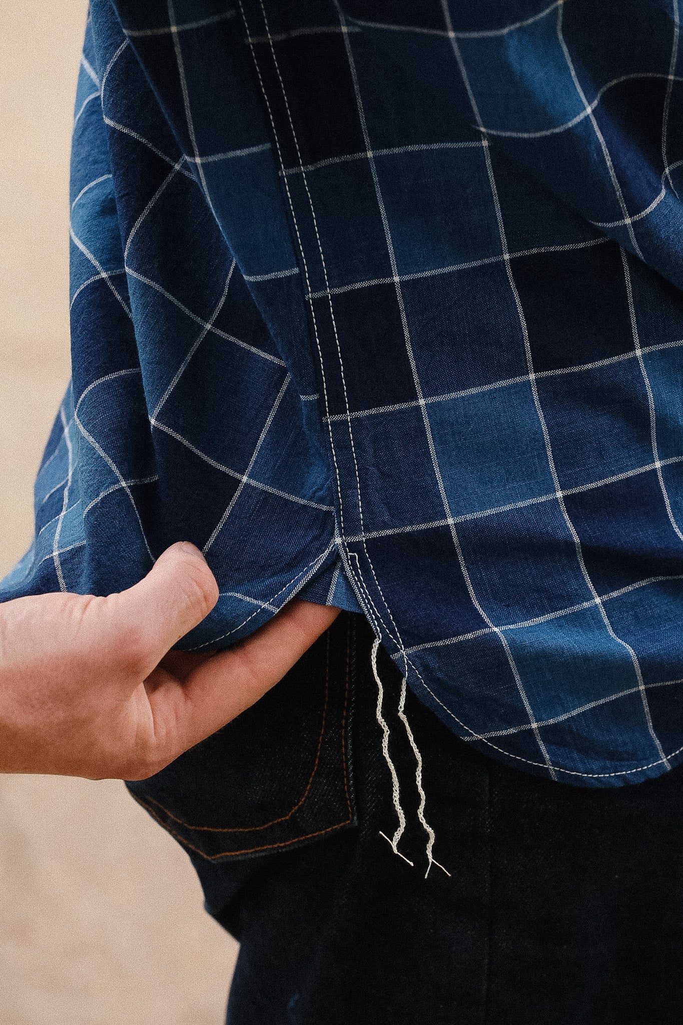 Close-up of a person wearing a blue checkered shirt with a blurred background
