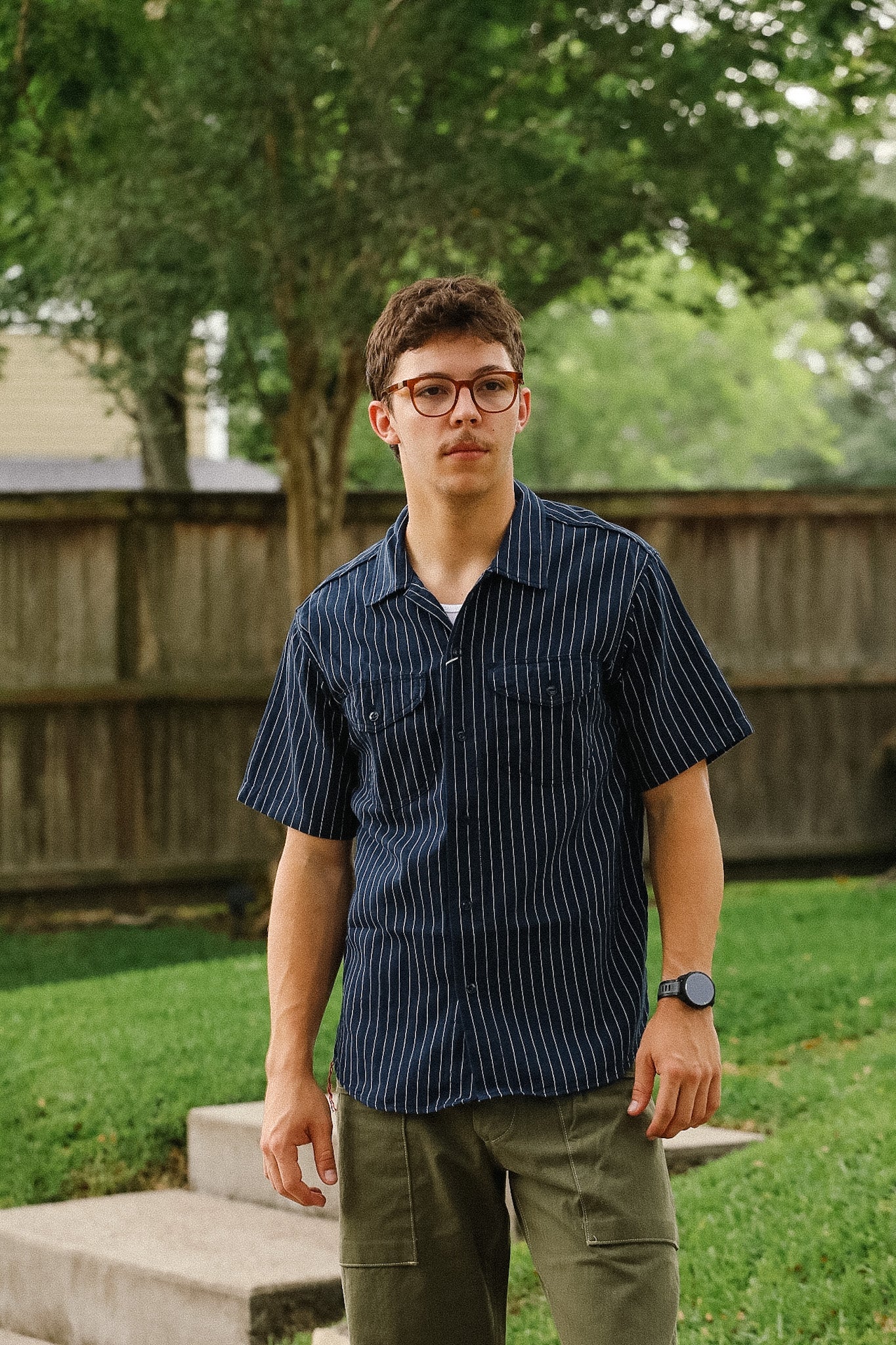 Person wearing a striped shirt and glasses outdoors