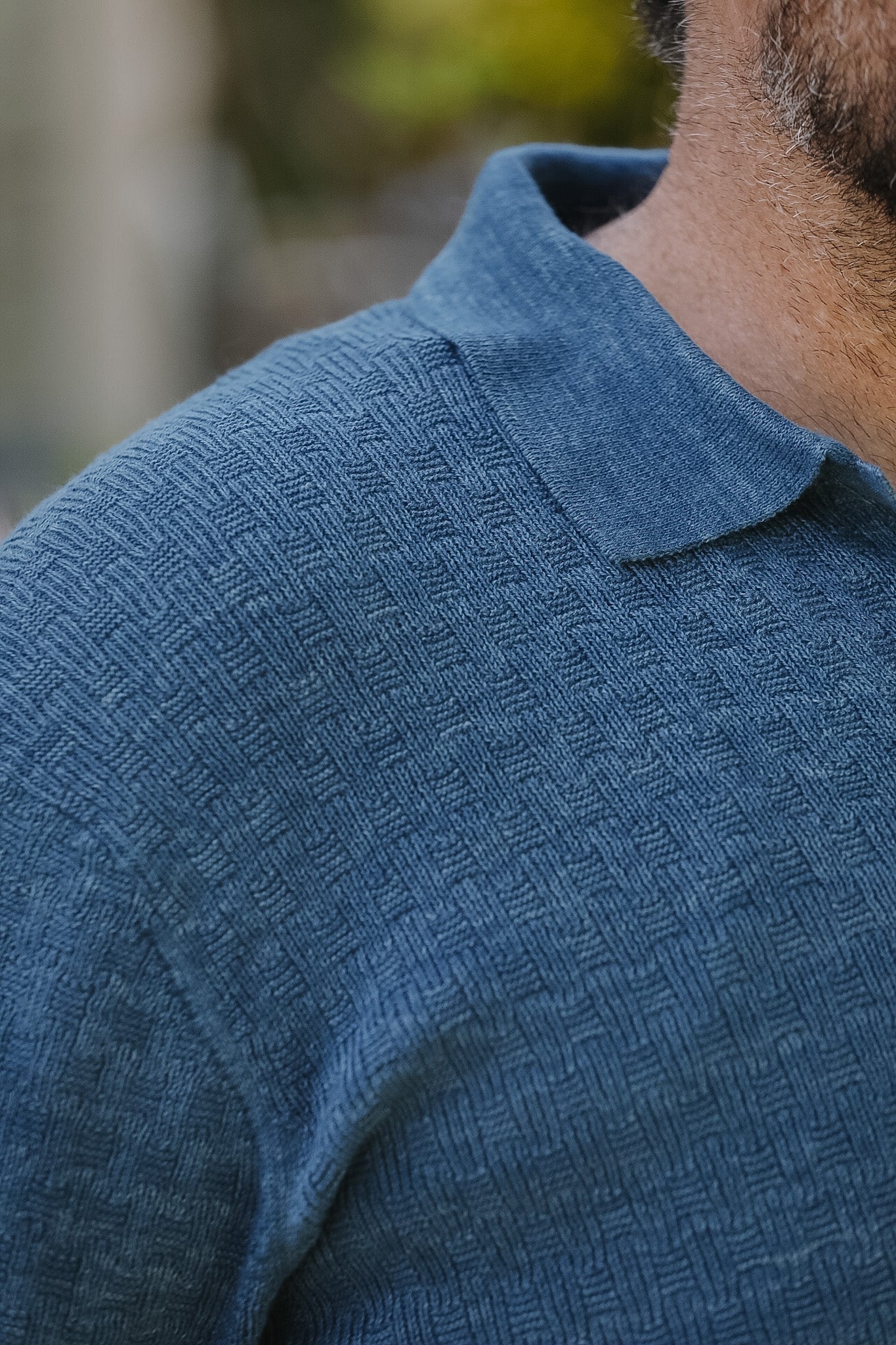 Close-up of a person wearing a textured blue shirt with a blurred background