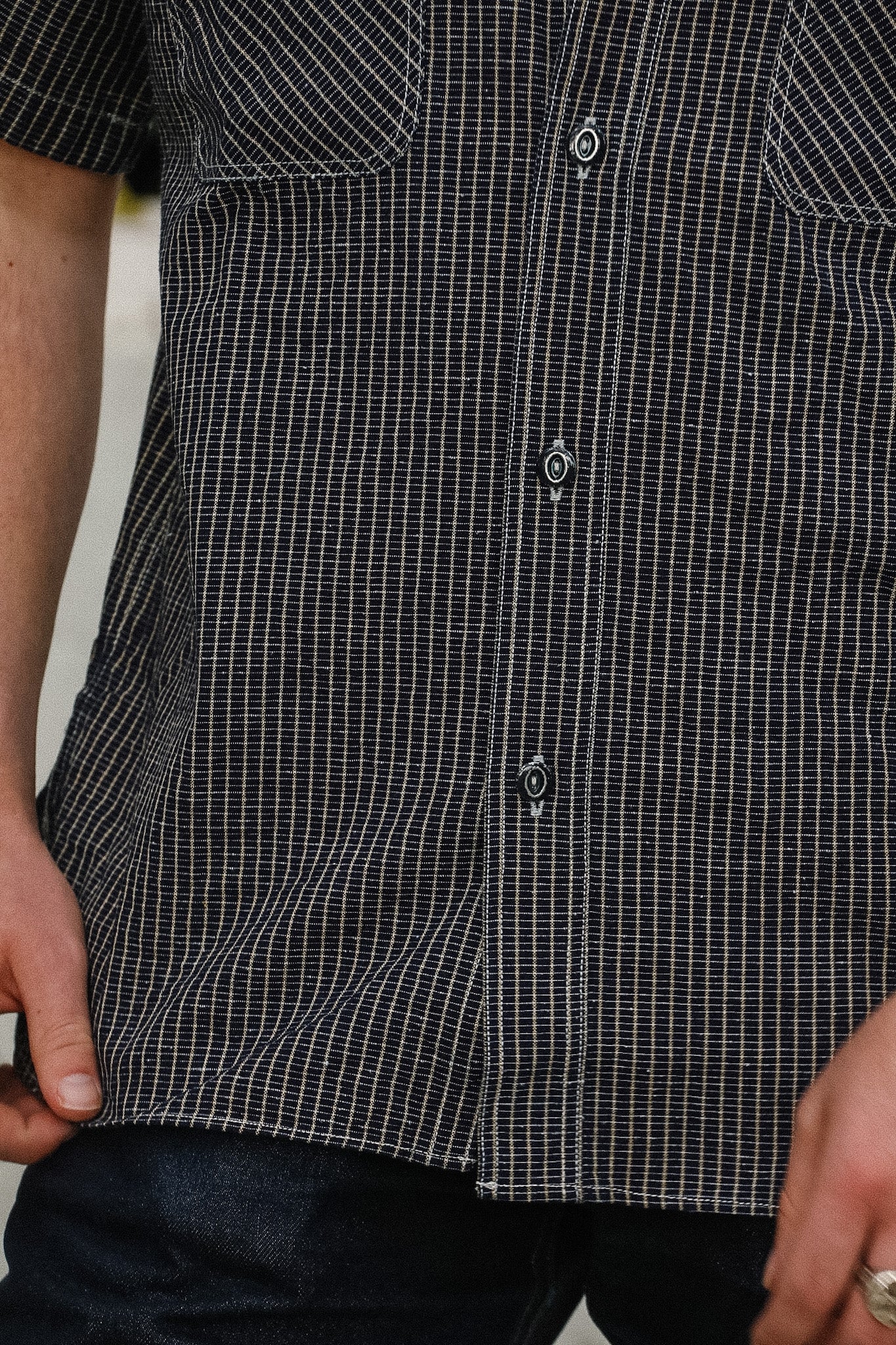 Close-up of a person wearing a black and white checkered shirt with a blurred background
