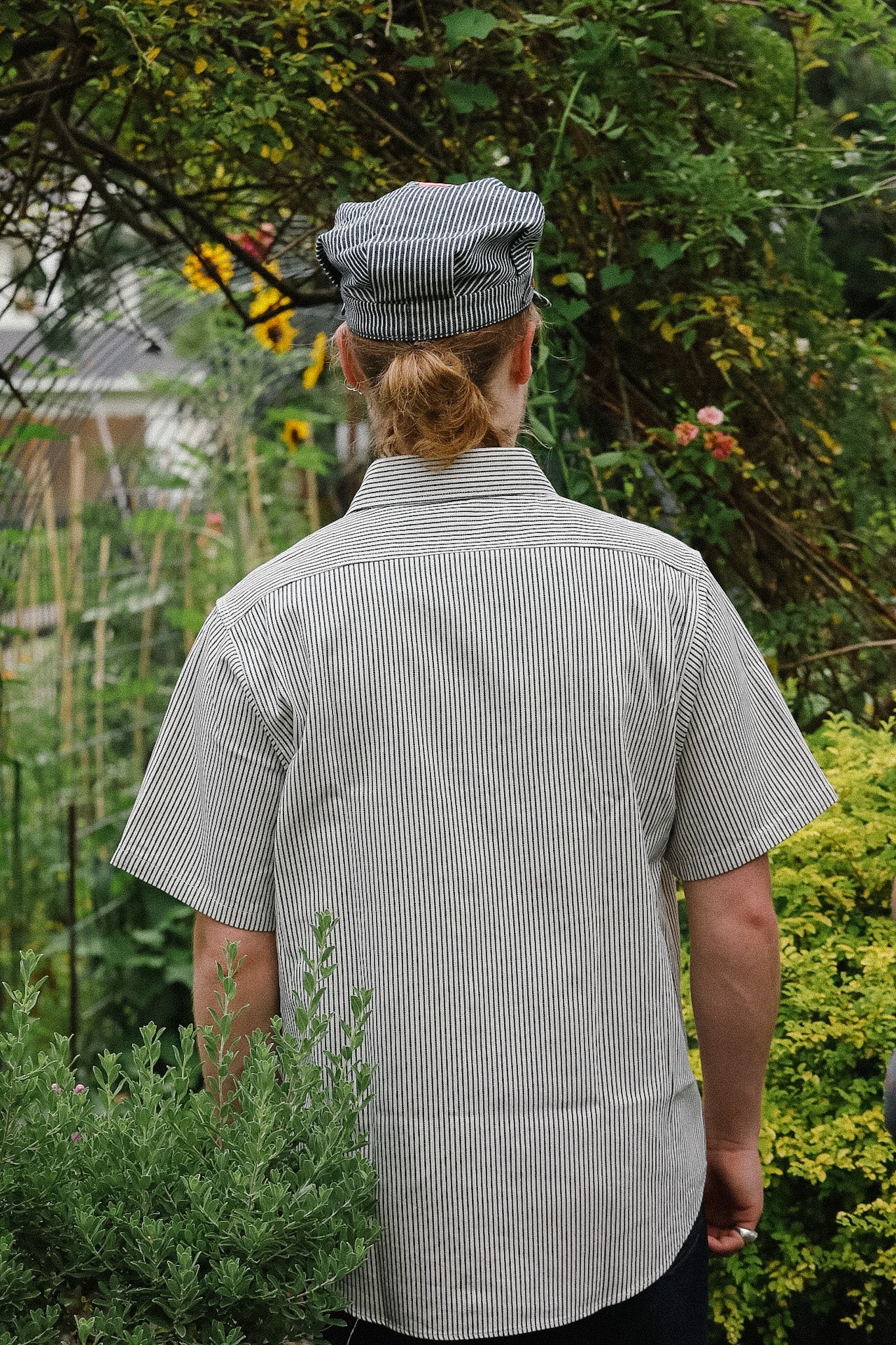 Person wearing a checkered shirt and cap in a garden setting