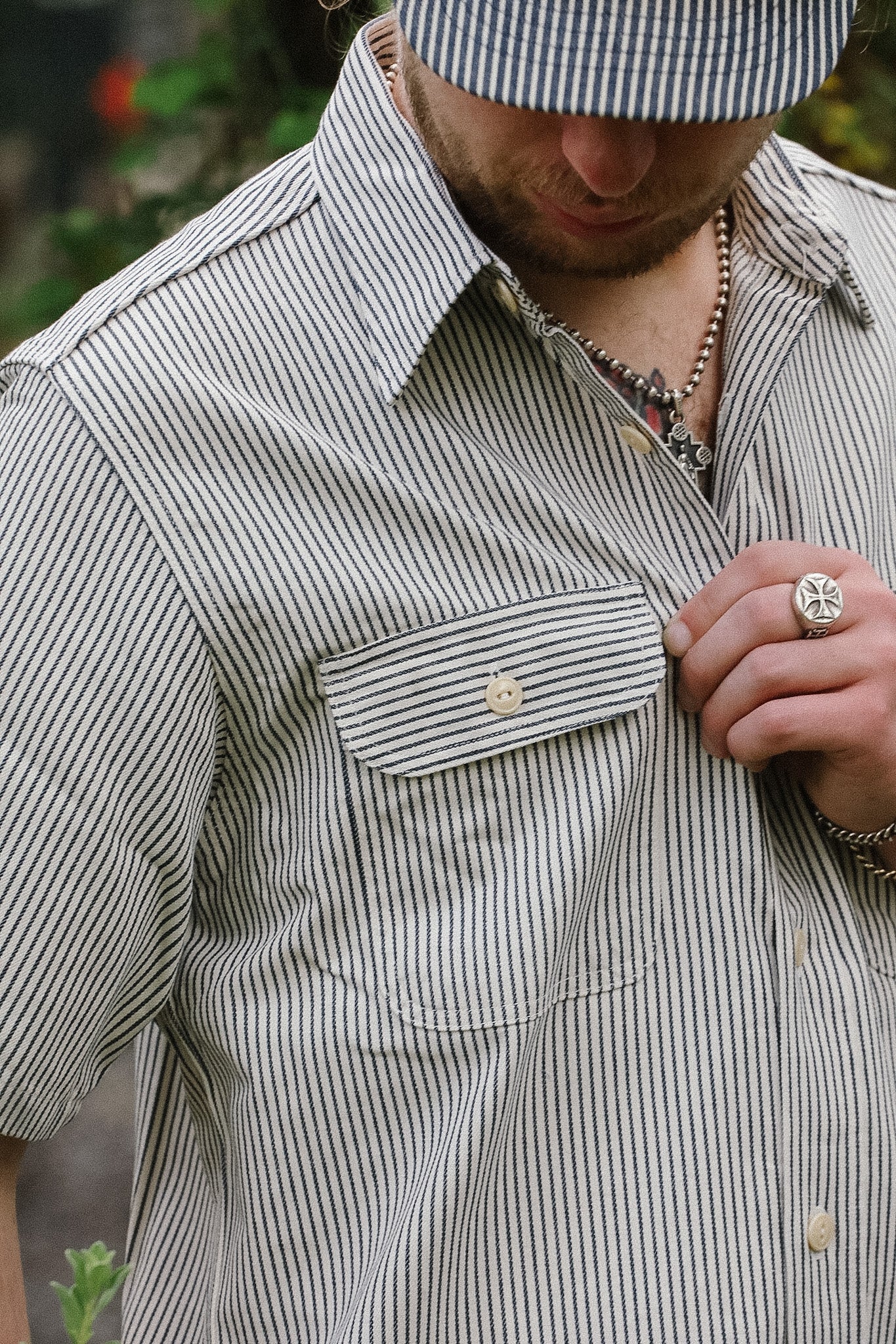 Man wearing a striped shirt and cap, with a focus on the shirt's pocket and collar.