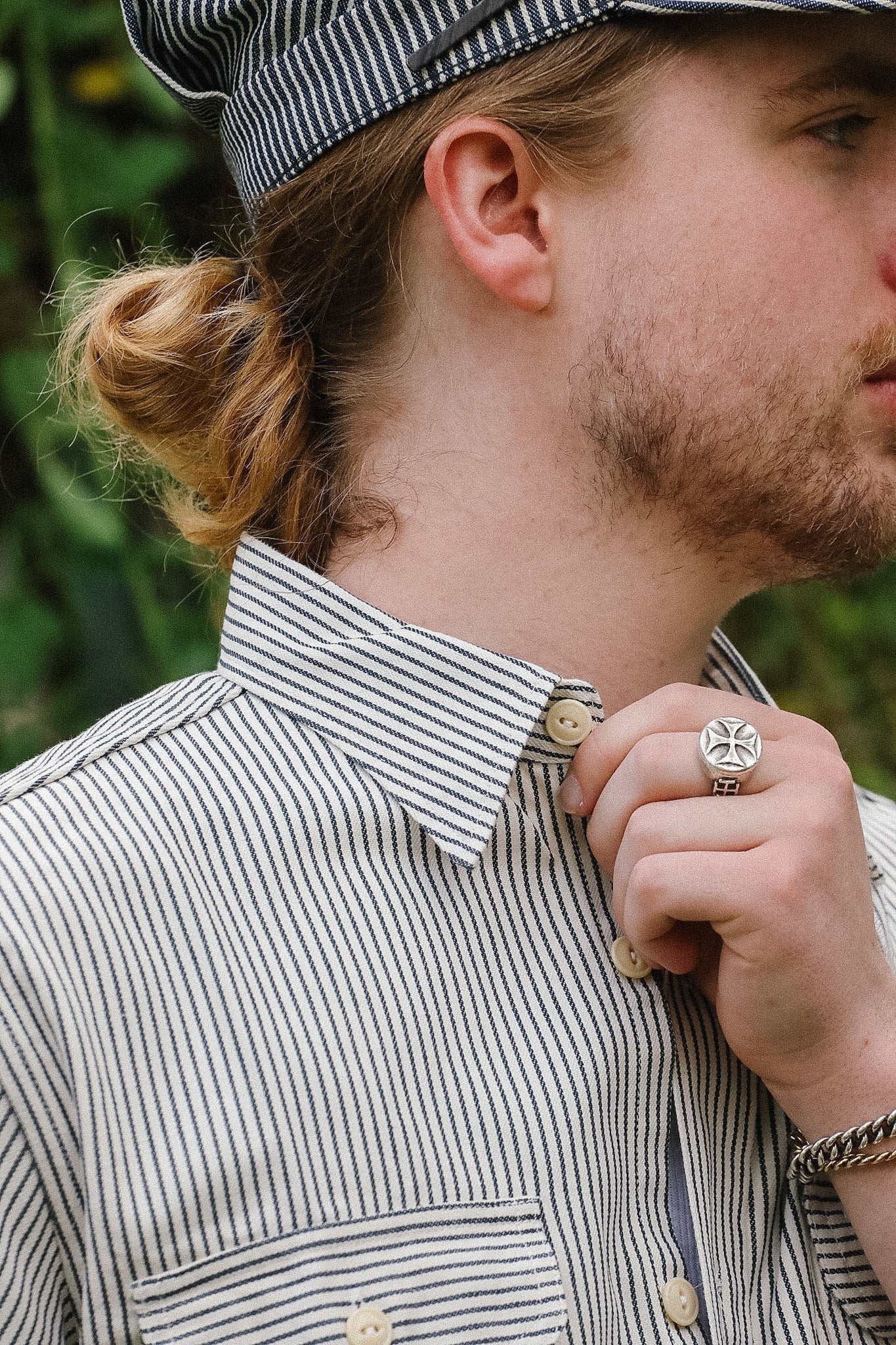 Man wearing a striped shirt with a focus on his collar and hand adjusting it.