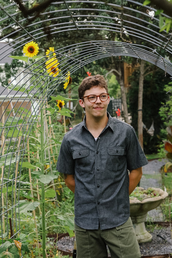 Man standing in a garden with sunflowers and a metal archway
