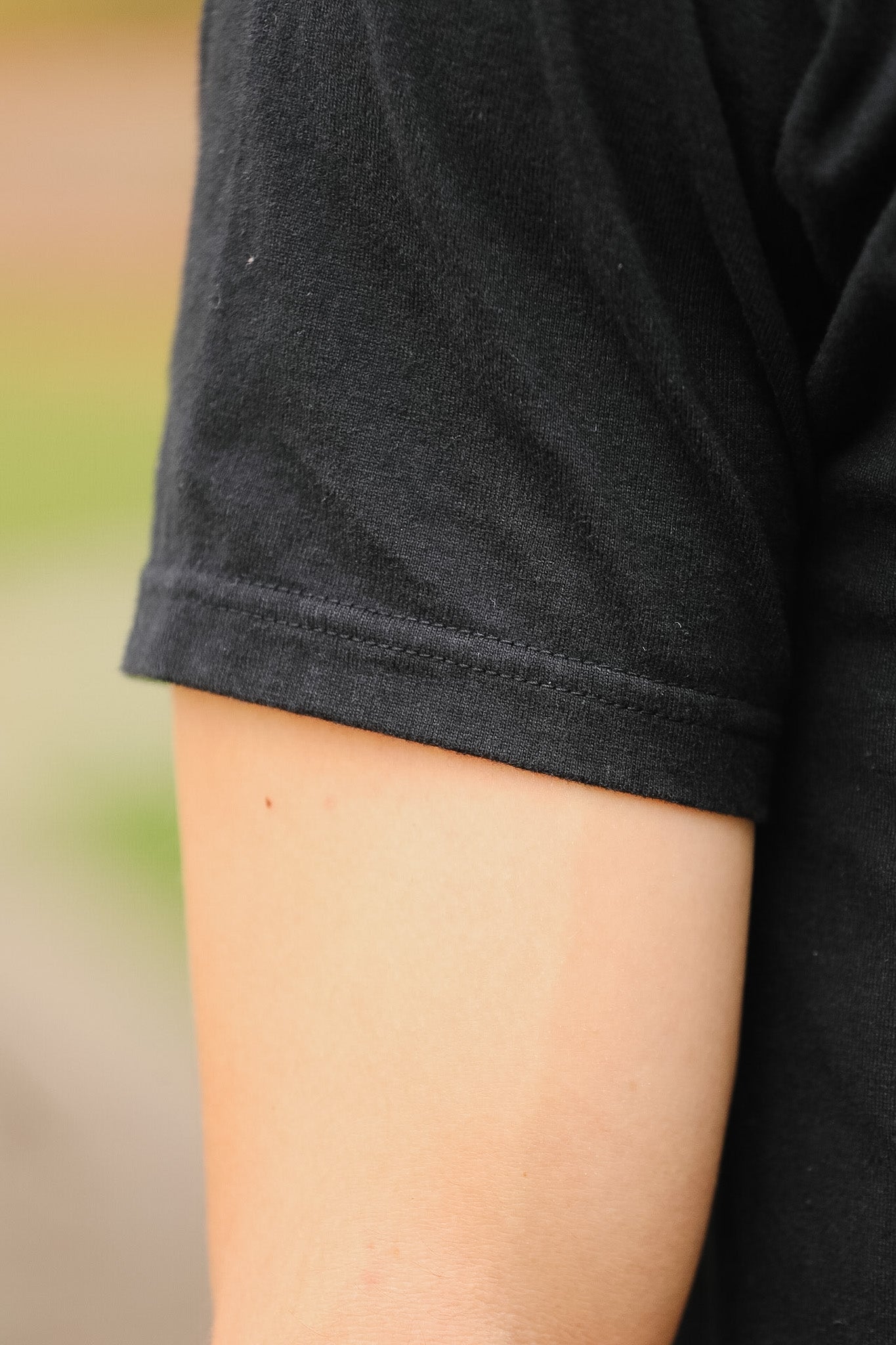 Close-up of a person wearing a black t-shirt with a blurred background