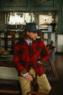 Man wearing a red plaid shirt and cap in a casual setting