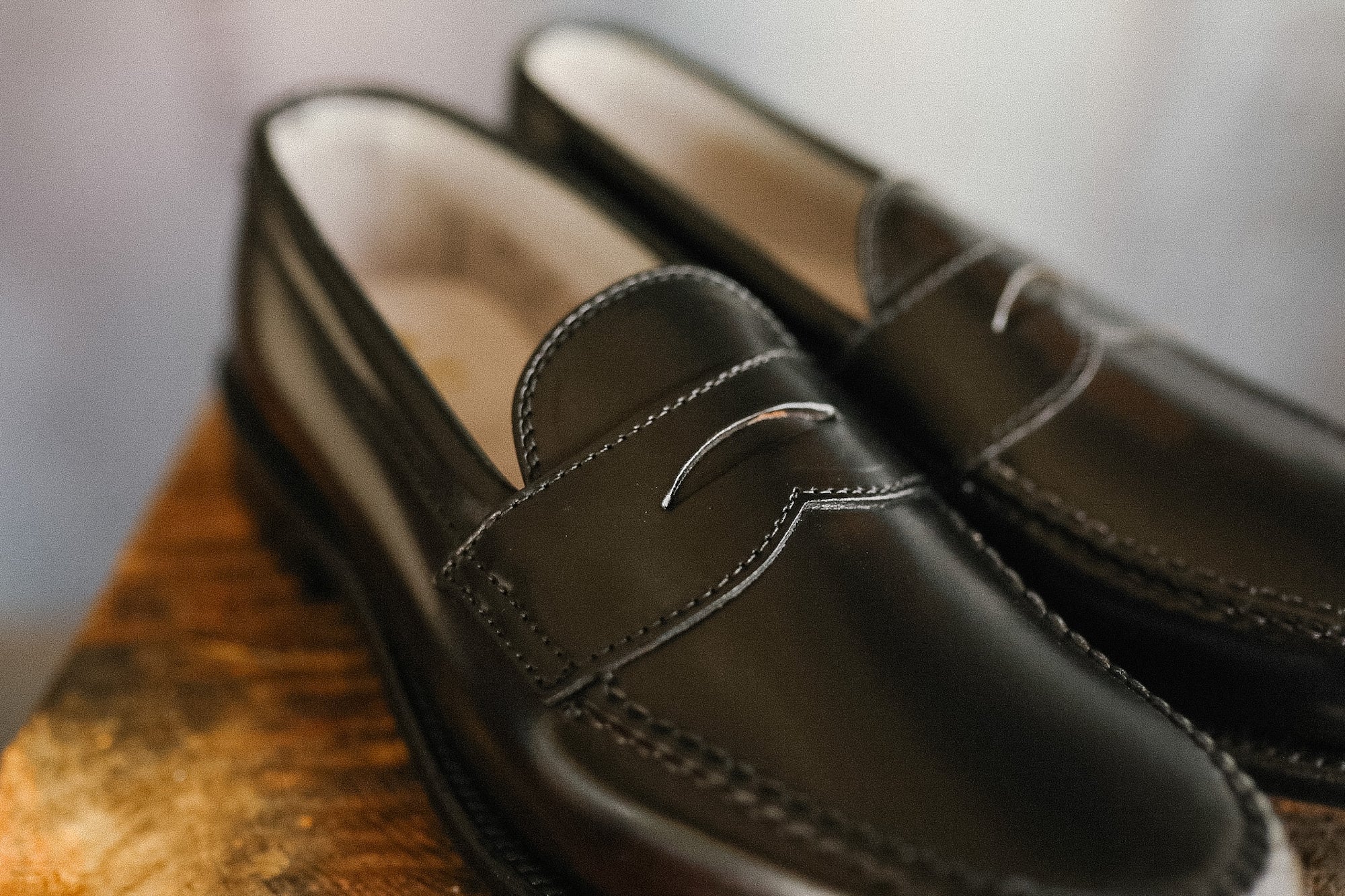Pair of black leather loafers on a wooden surface with a blurred background