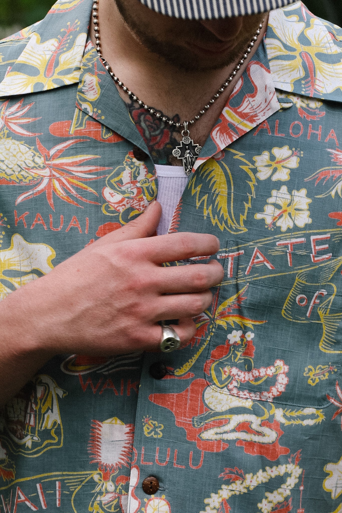 Person wearing a colorful Hawaiian shirt with floral and text patterns.