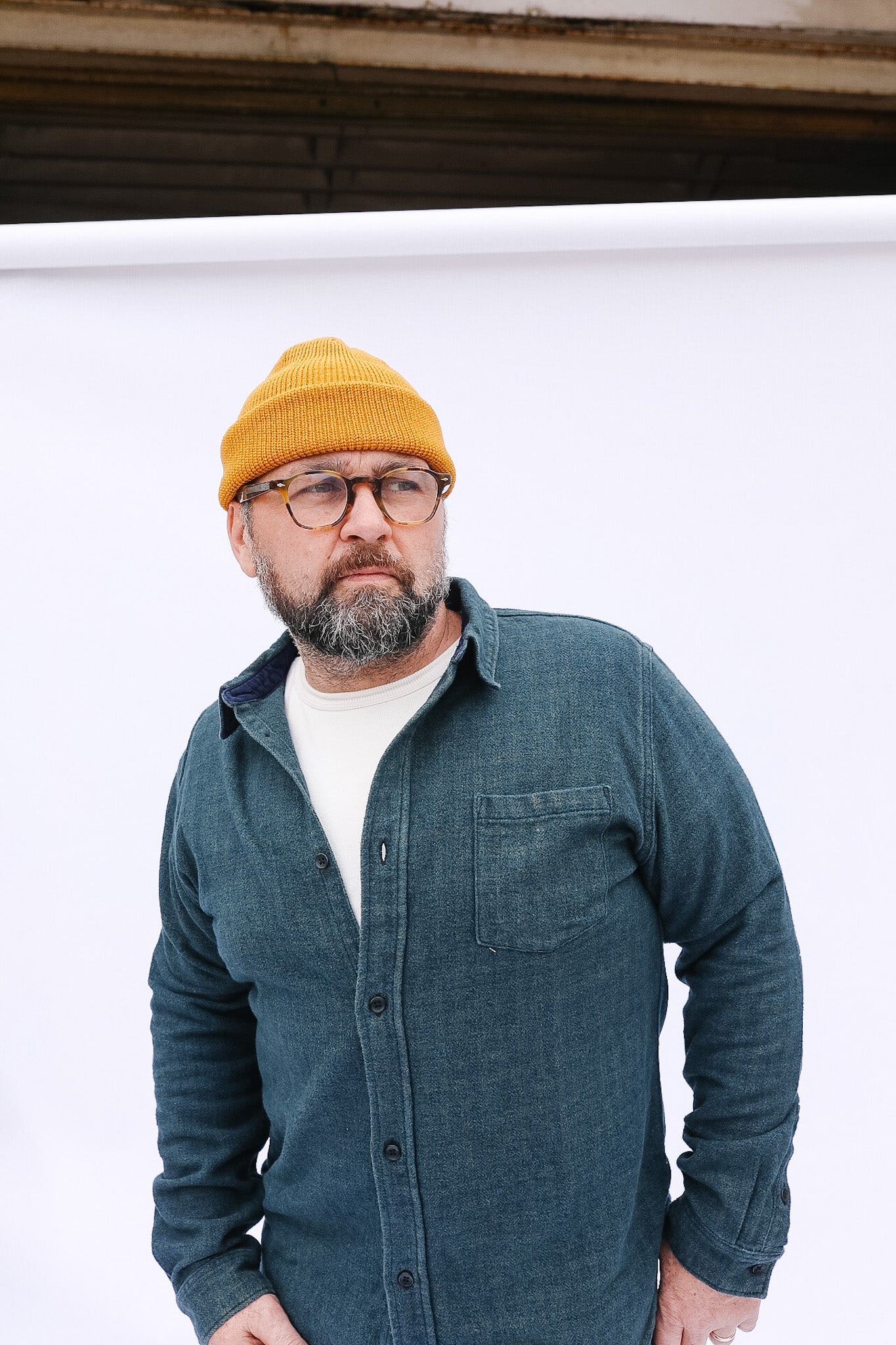 Man wearing a yellow beanie and blue shirt against a white background