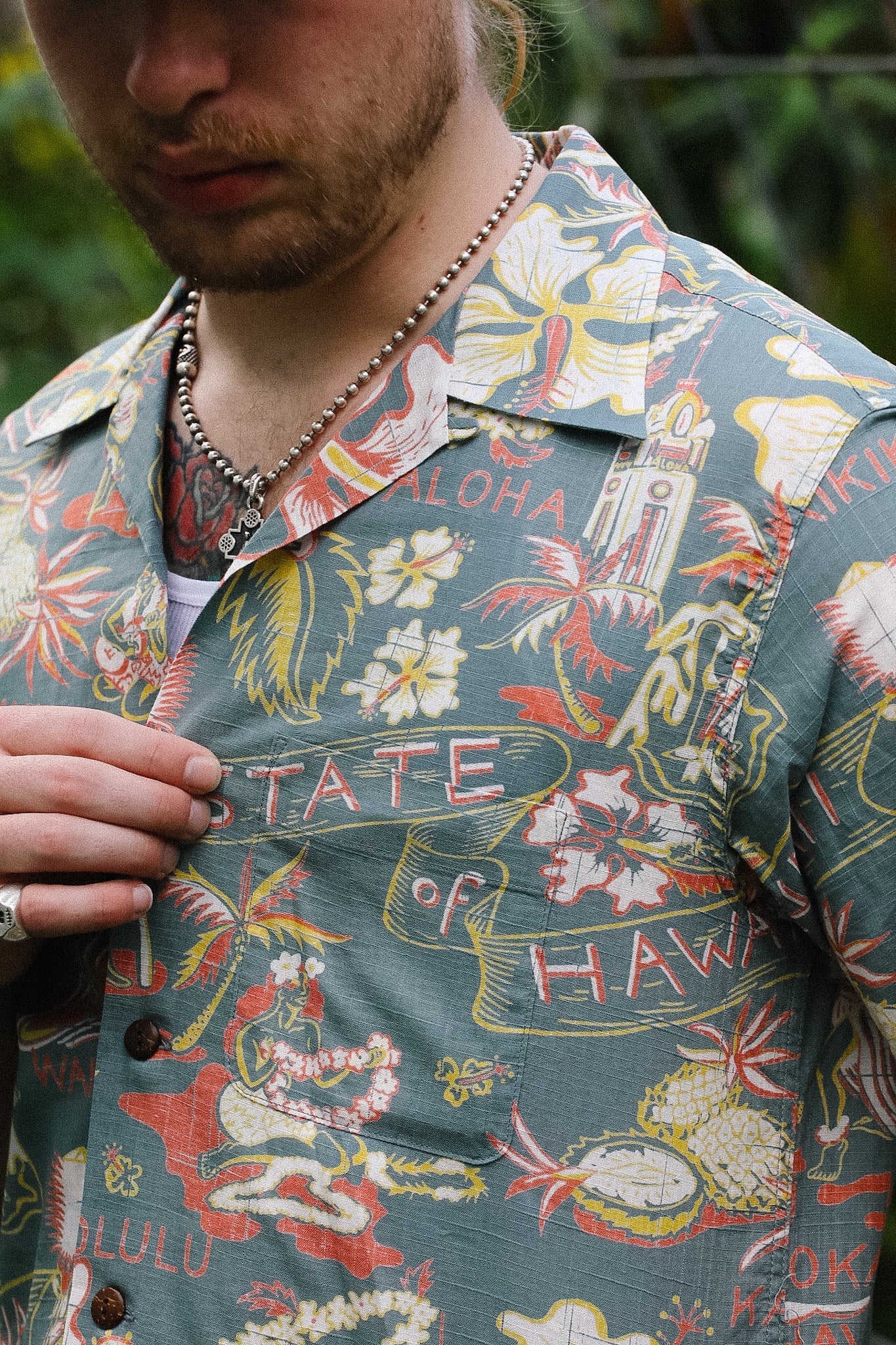 Person wearing a colorful Hawaiian shirt with floral and text patterns.