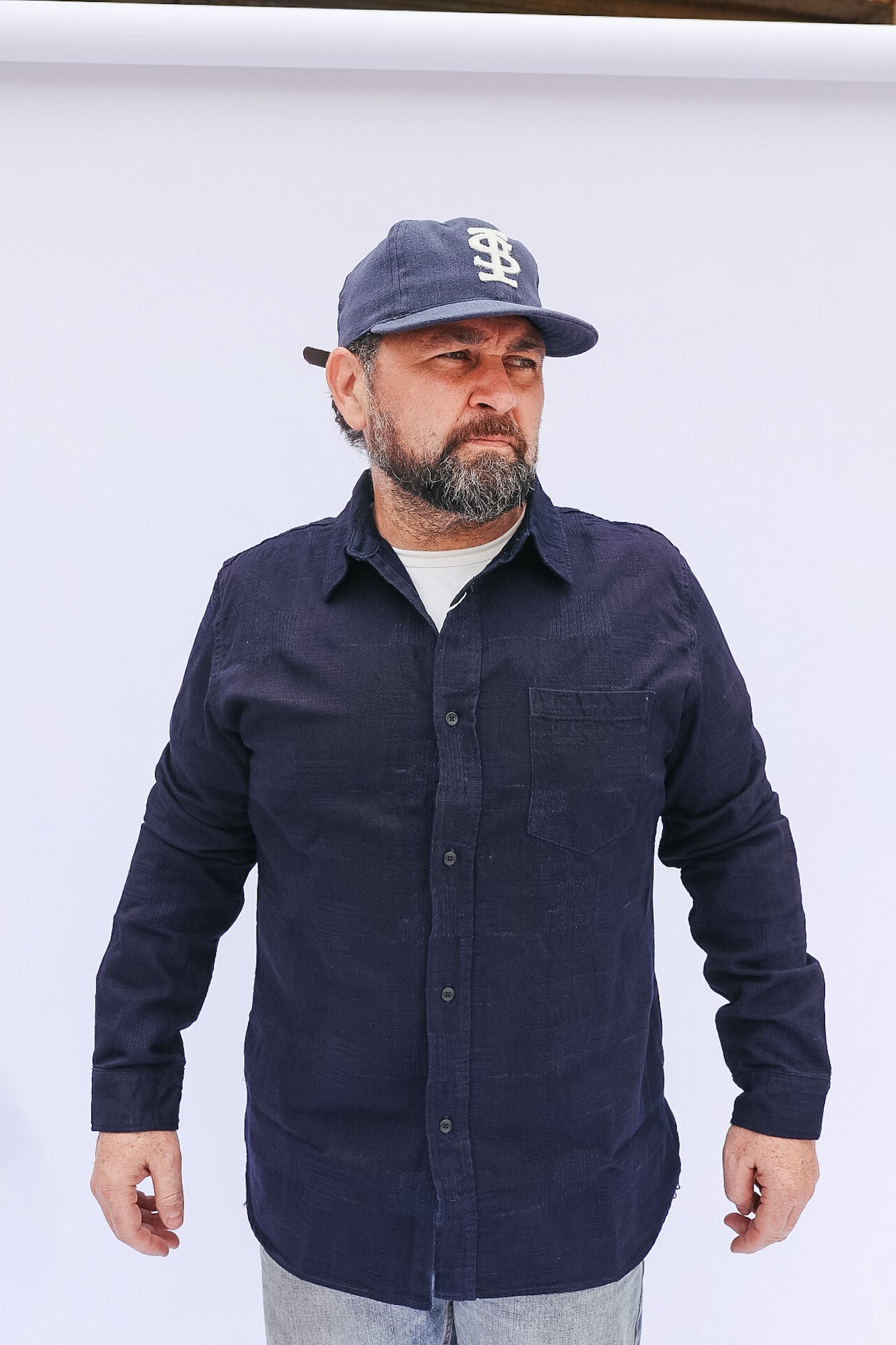 Man wearing a navy blue shirt and cap on a white background