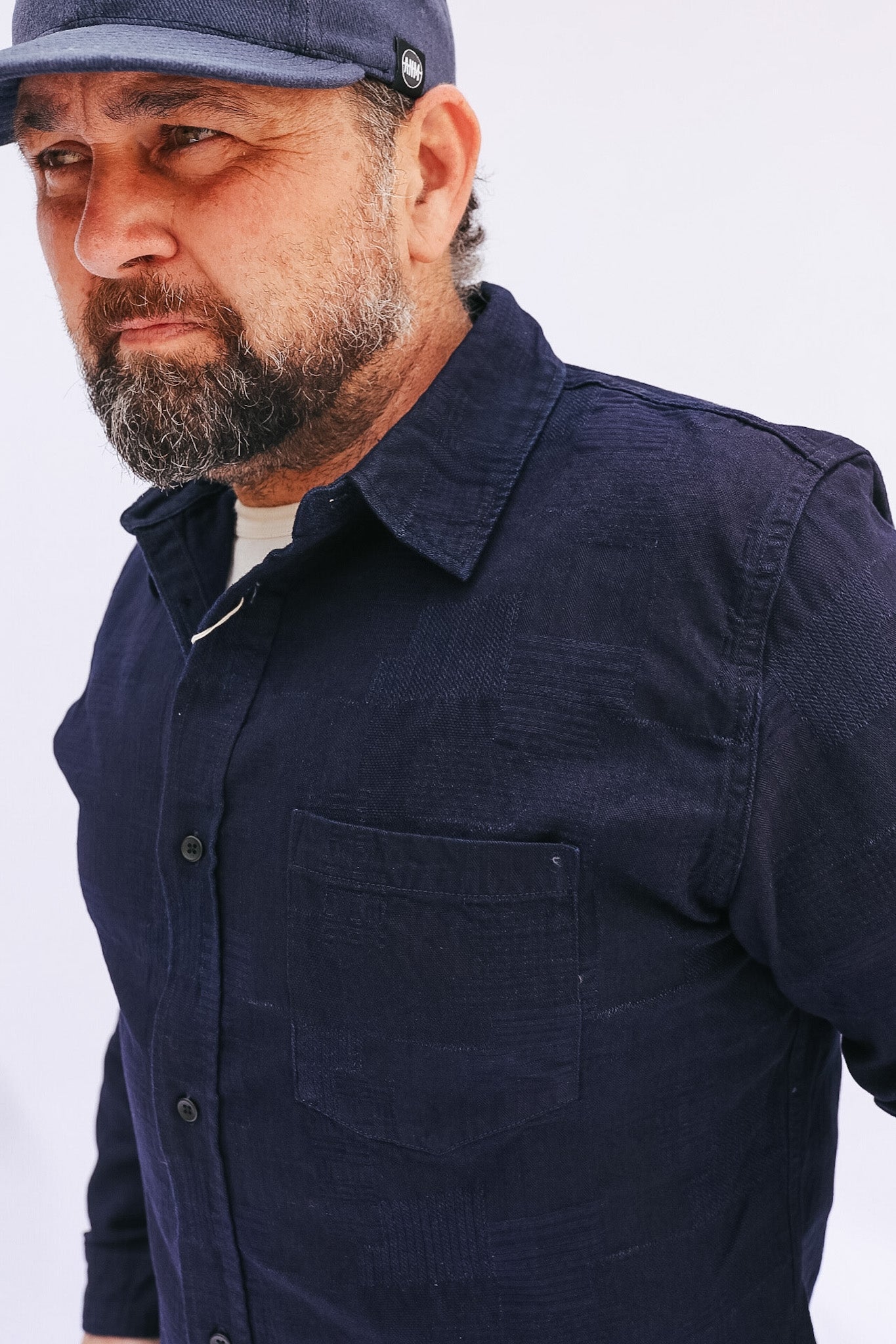 Man wearing a navy blue shirt and cap against a white background