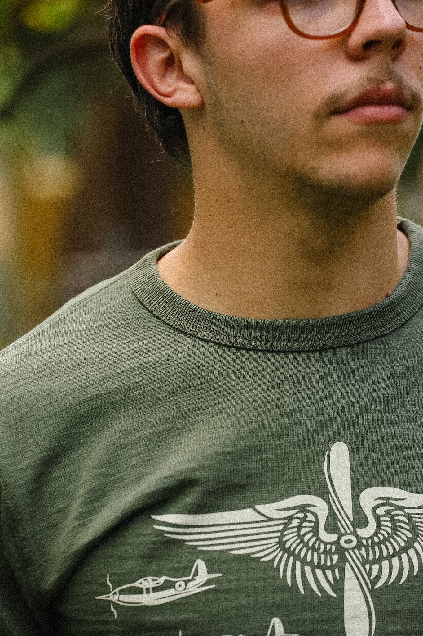 Close-up of a person wearing a green t-shirt with a white graphic design.