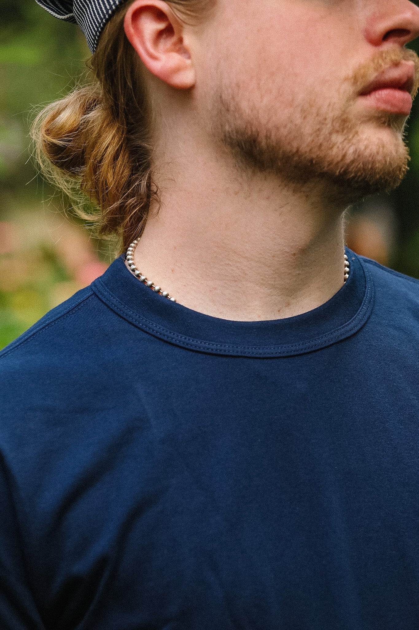 Man wearing a blue shirt with a blurred natural background
