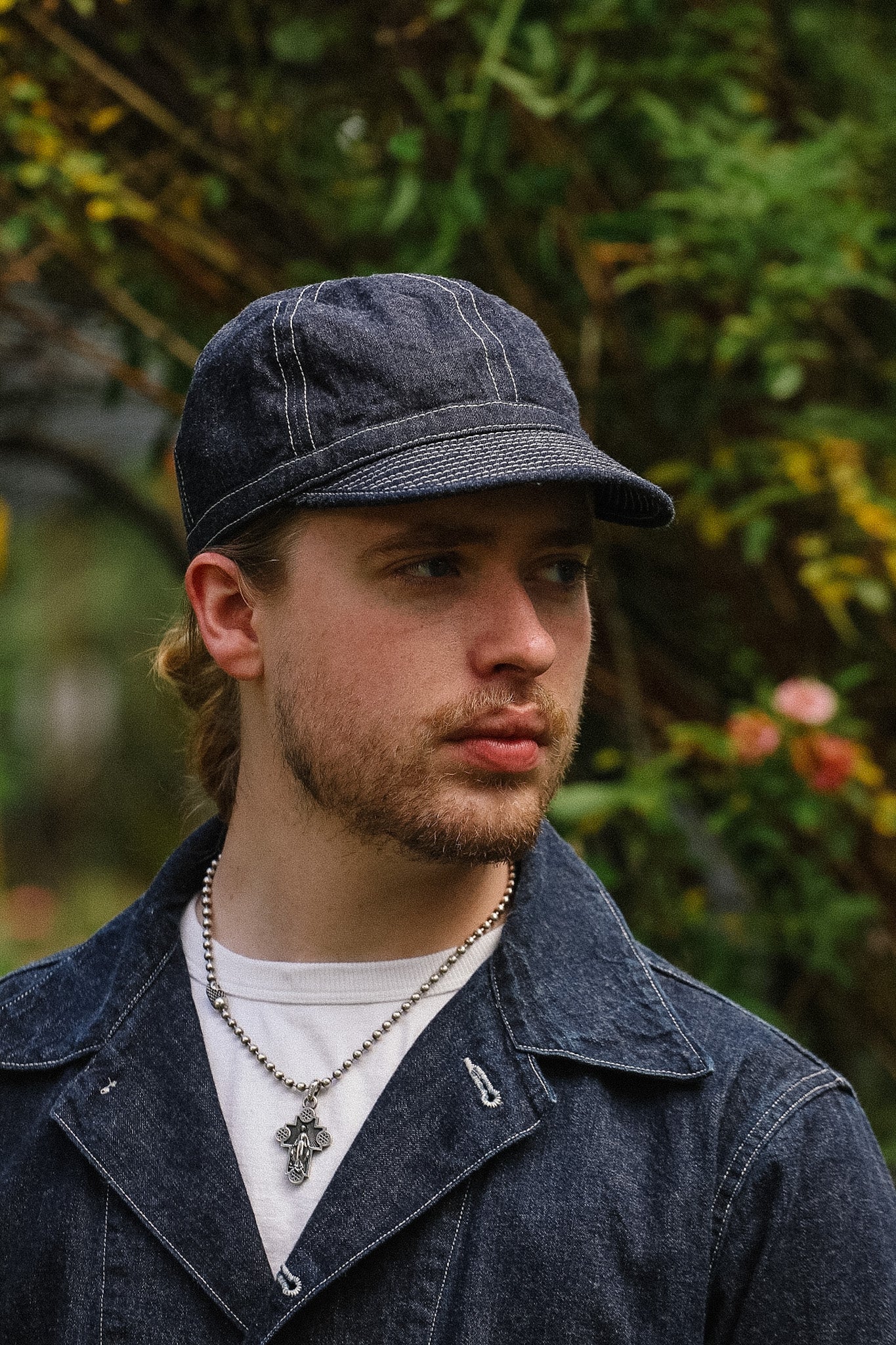 Man wearing a denim cap and jacket with a blurred natural background