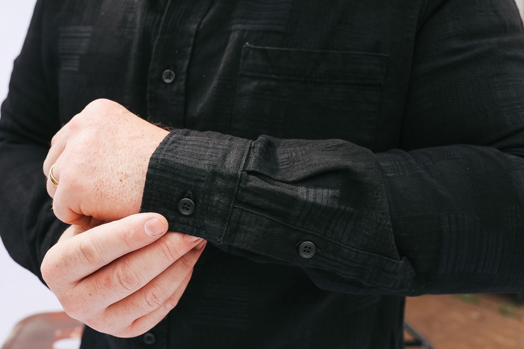 Person wearing a black shirt with rolled-up sleeves, adjusting the cuff.